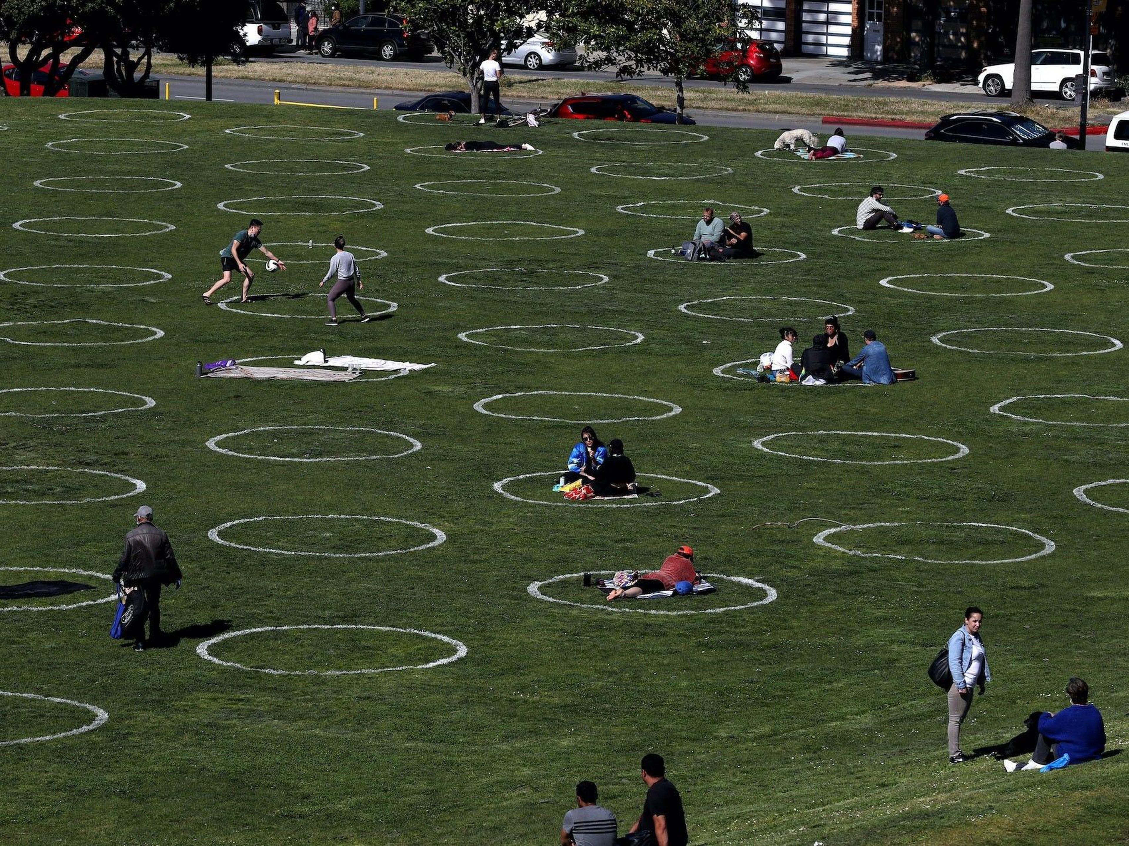 La gente se sienta en círculos de distanciamiento social en el Parque Dolores, el 20 de mayo de 2020, en San Francisco, California, EEUU.