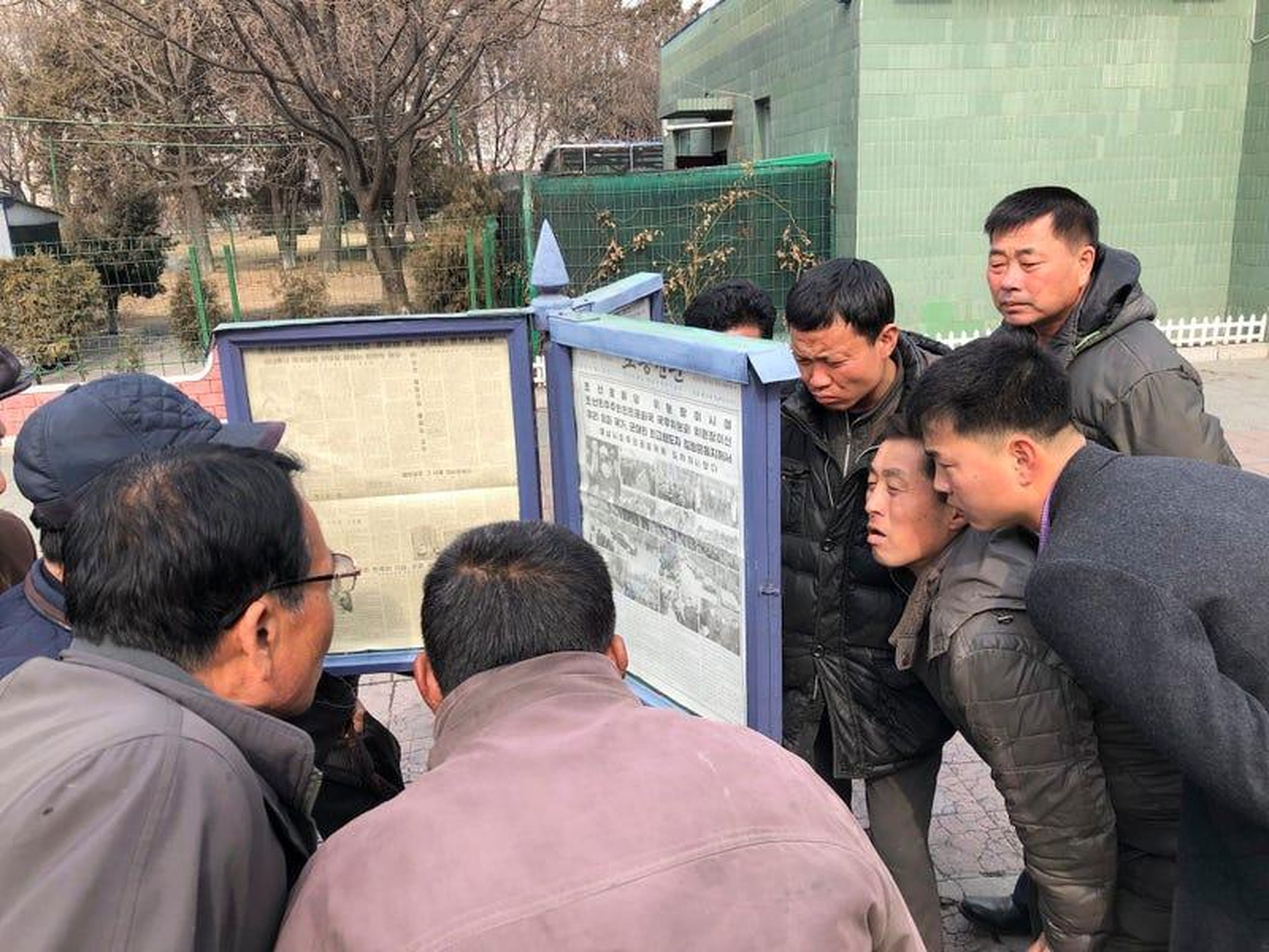 Los hombres se reúnen alrededor de las publicaciones del periódico público para leer sobre la visita del líder norcoreano Kim Jong Un a Vietnam.