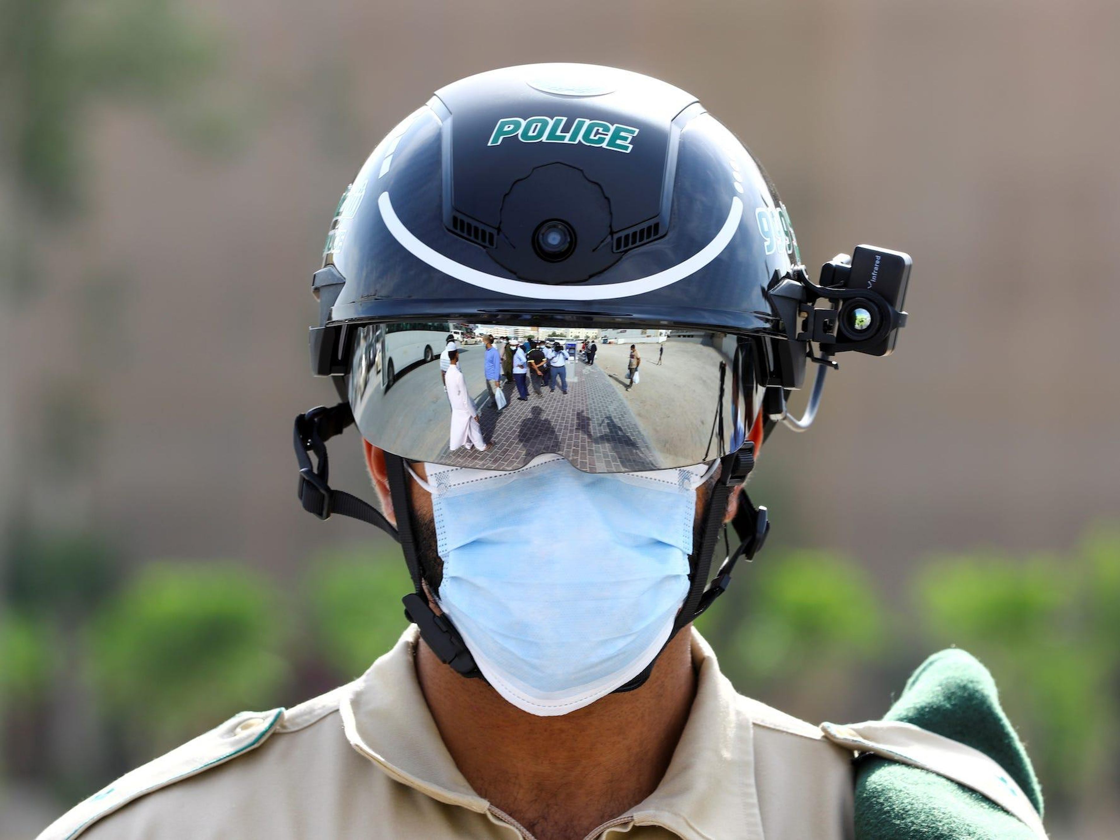 Un oficial de policía lleva un casco inteligente mientras lo usa para comprobar la temperatura de los trabajadores, durante el brote de la enfermedad coronavirus (COVID-19) en Dubái