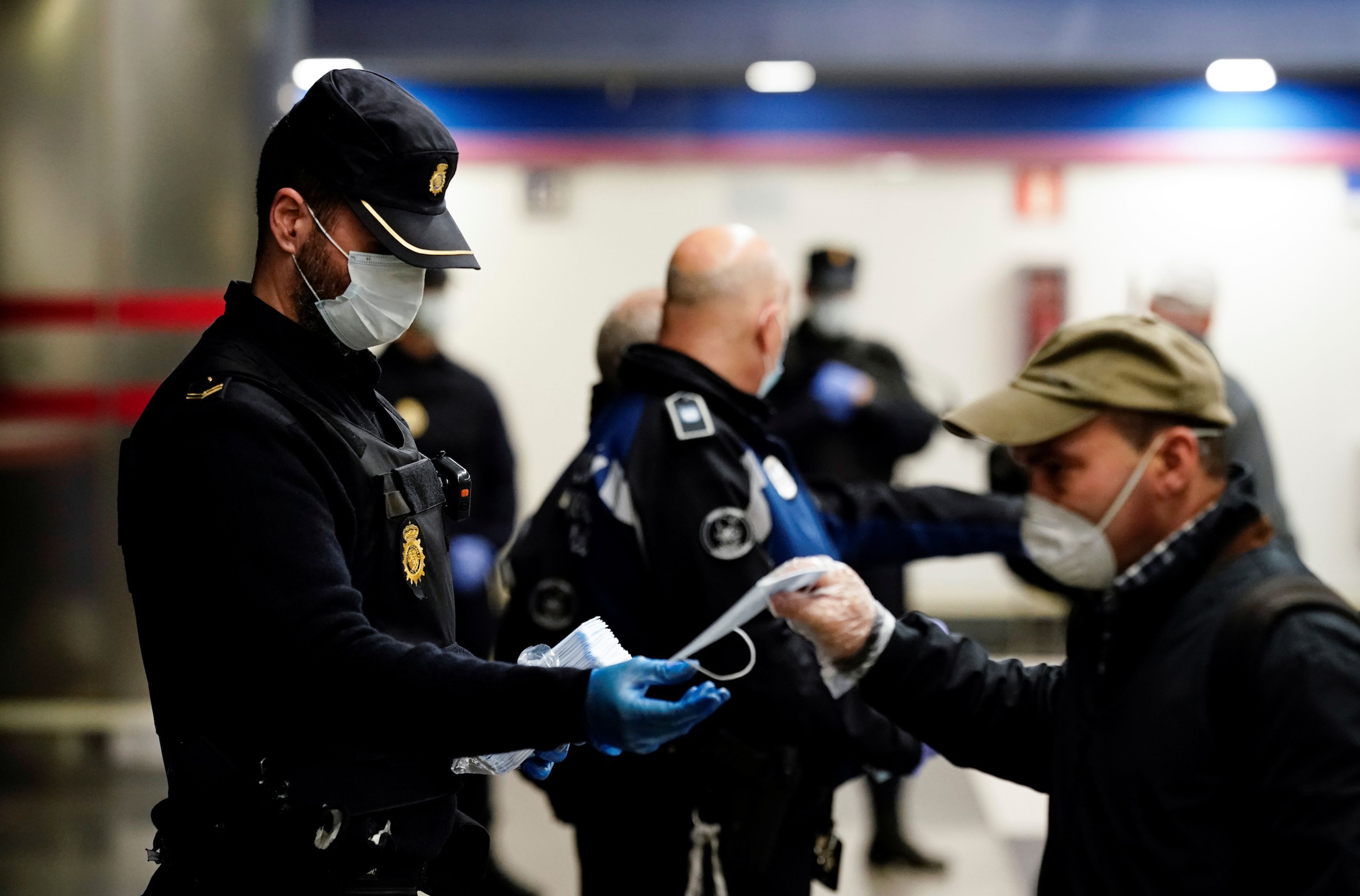 Un policía reparte mascarillas en el metro de Madrid.