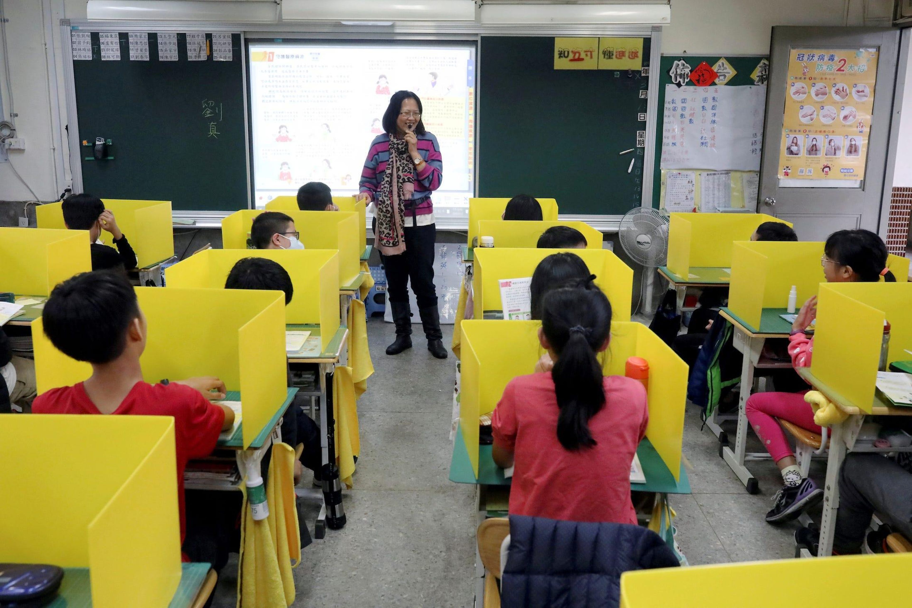 Los alumnos se sientan en escritorios con divisores amarillos, establecidos como medida contra el coronavirus, en la escuela primaria Dajia de Taipei, Taiwán, el 13 de marzo de 2020.