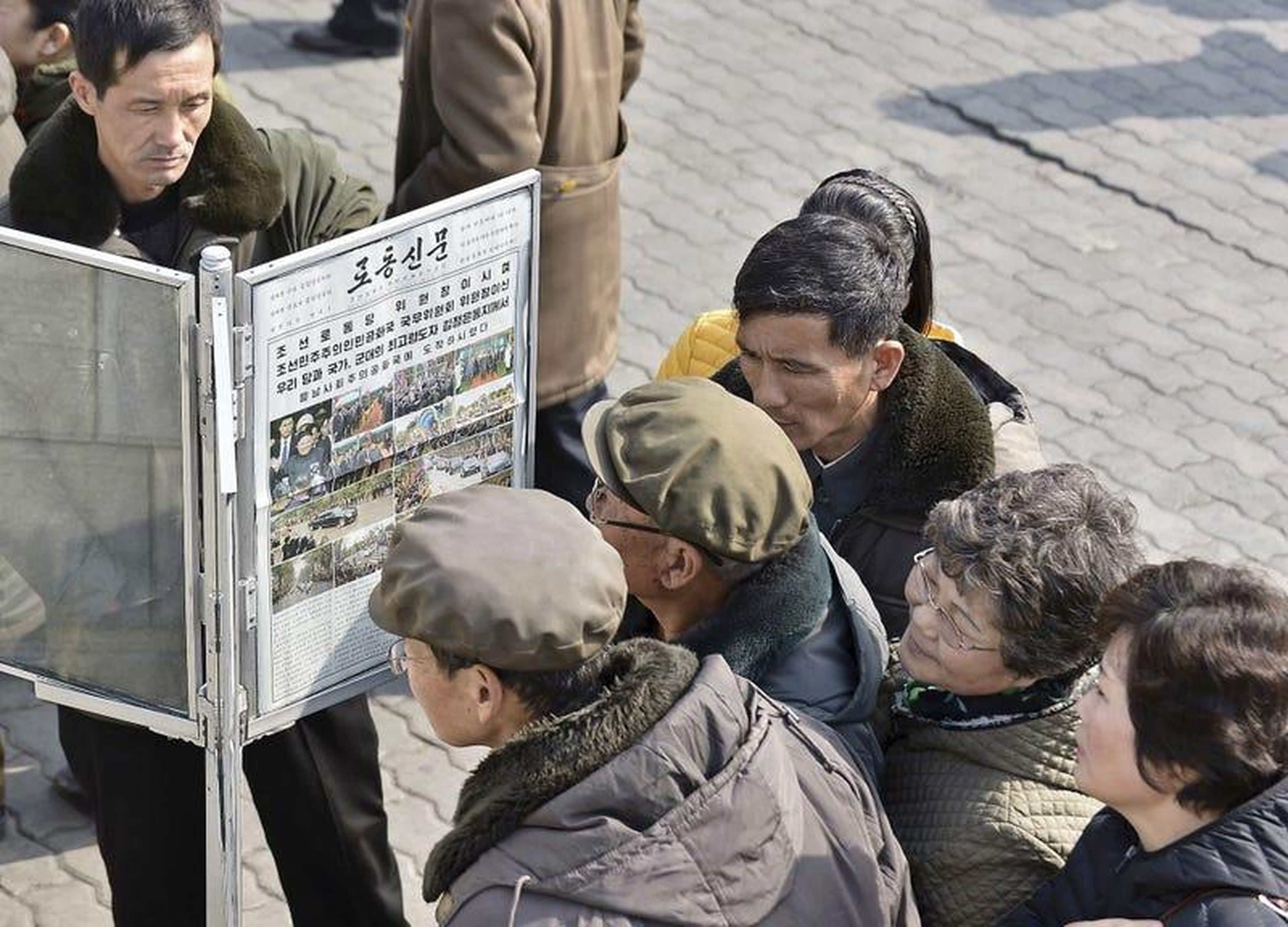 Los hombres se reúnen alrededor de las publicaciones del periódico público en Pyongyang en Pyongyang.