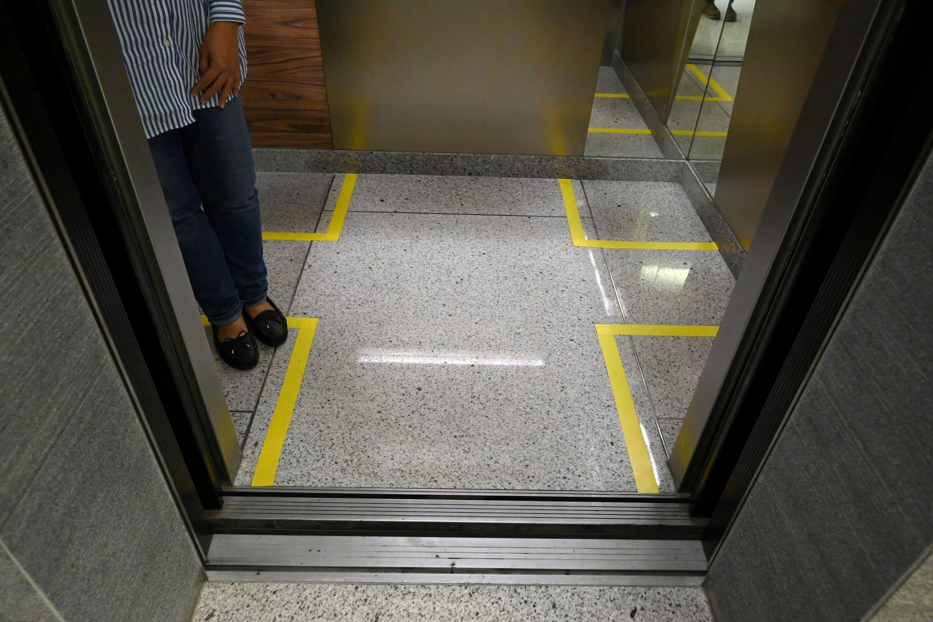 Áreas marcadas para delimitar las distancias entre personas en un ascensor de un edificio de oficinas en Singapur el 31 de marzo de 2020.