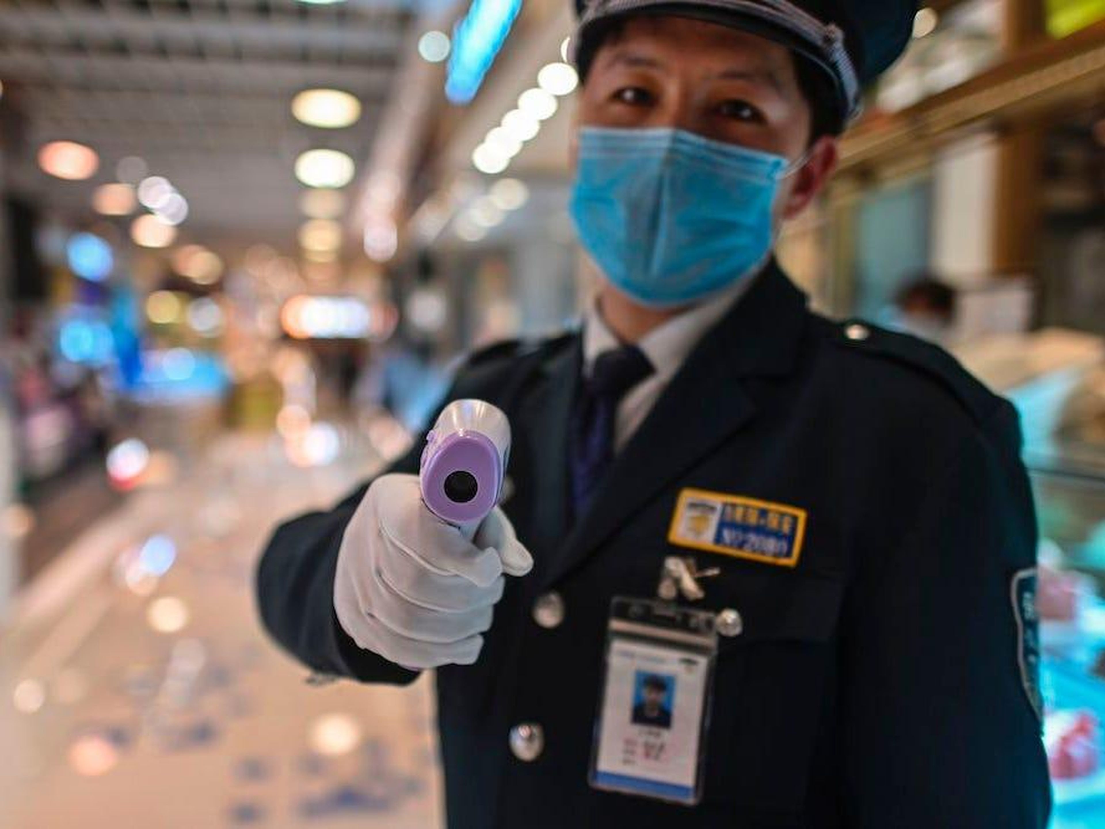 Un guardia de seguridad sostiene una pistola térmica para verificar la temperatura corporal de los clientes en la entrada de un restaurante en Shanghai.