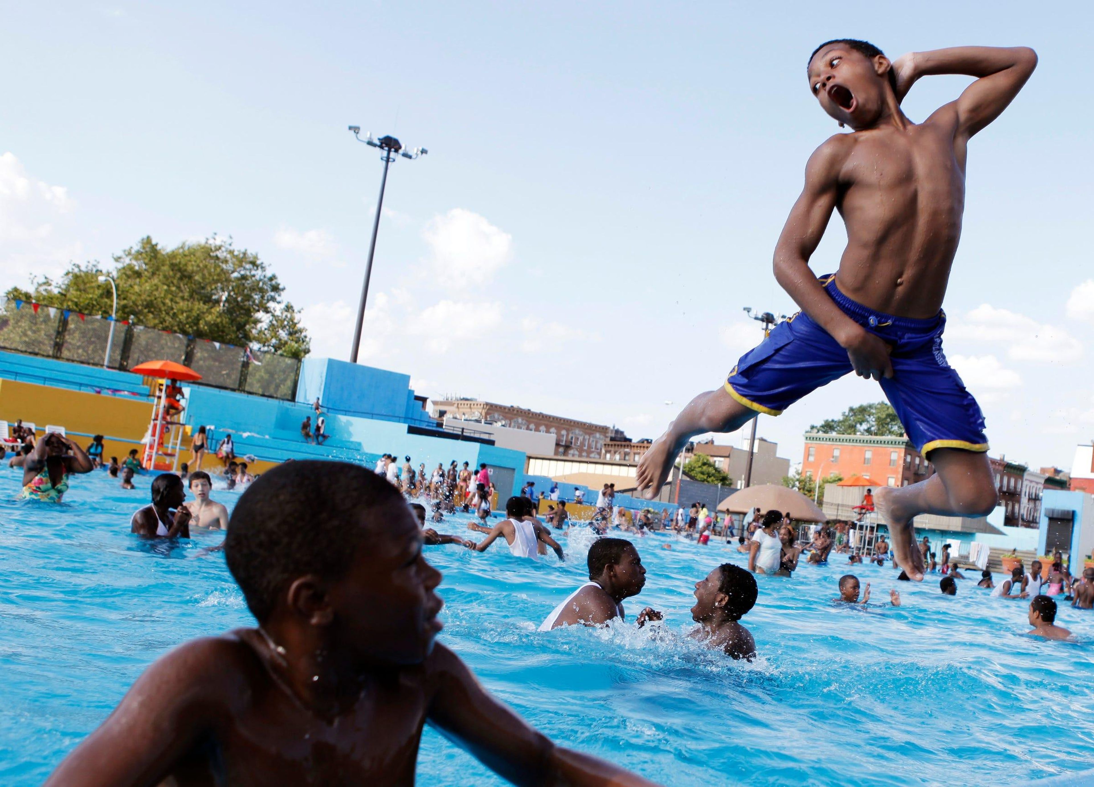 Unos niños nadan en una piscina pública.