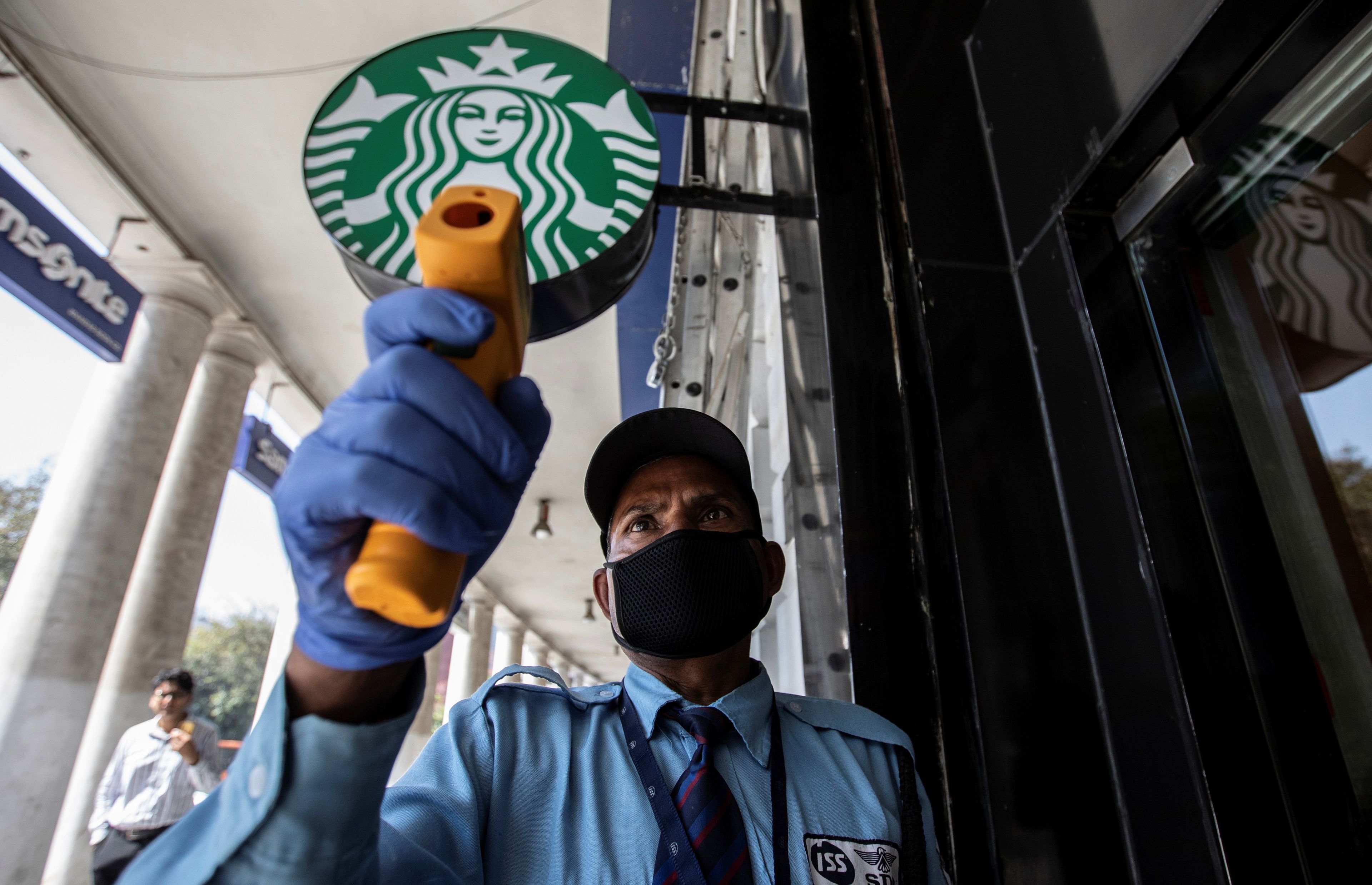 Un empleado controla la temperatura en la puerta de un Starbucks