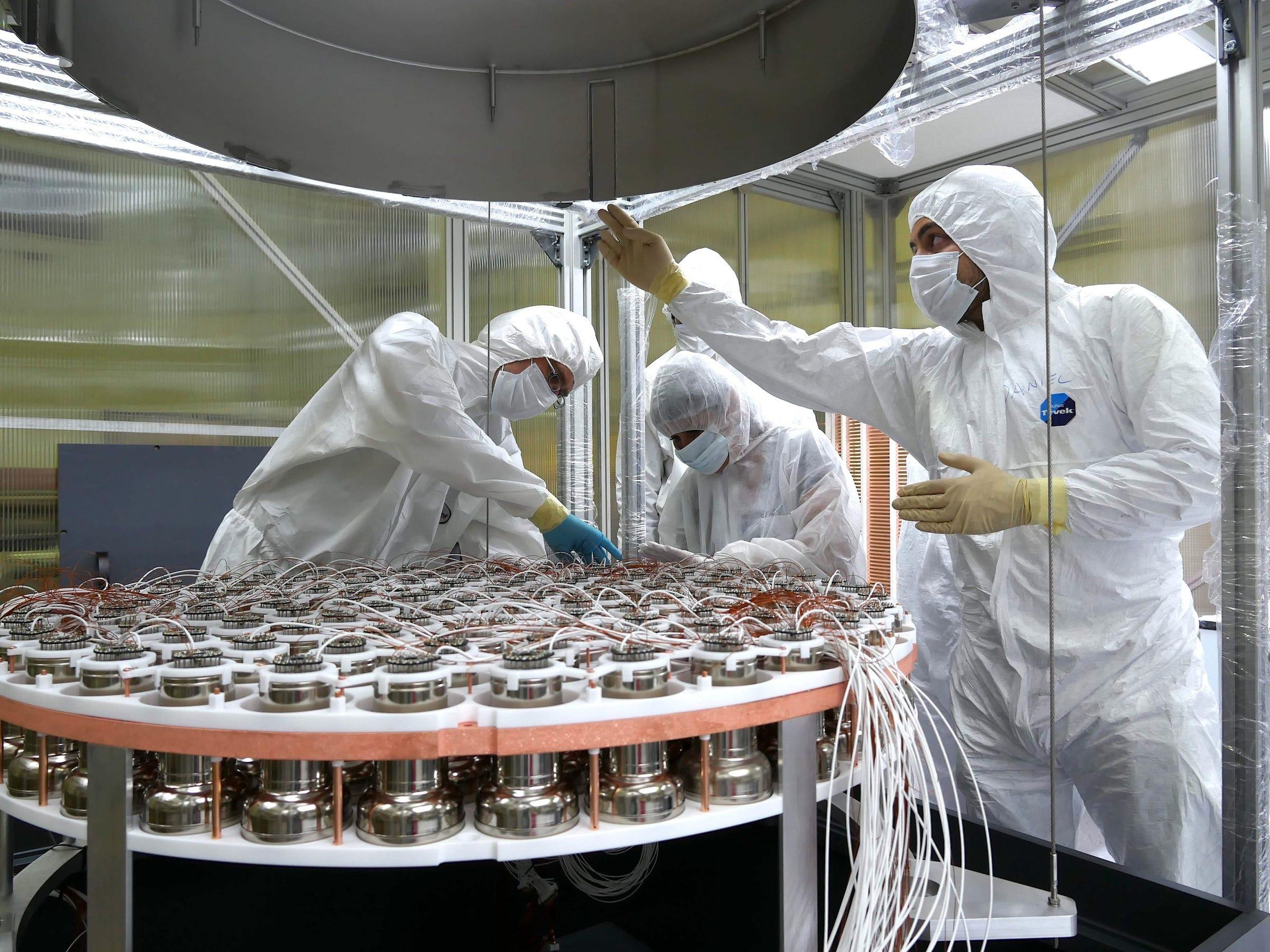 Experts construct the top array of photomultiplier tubes, which detect flashes of light from particle interactions.