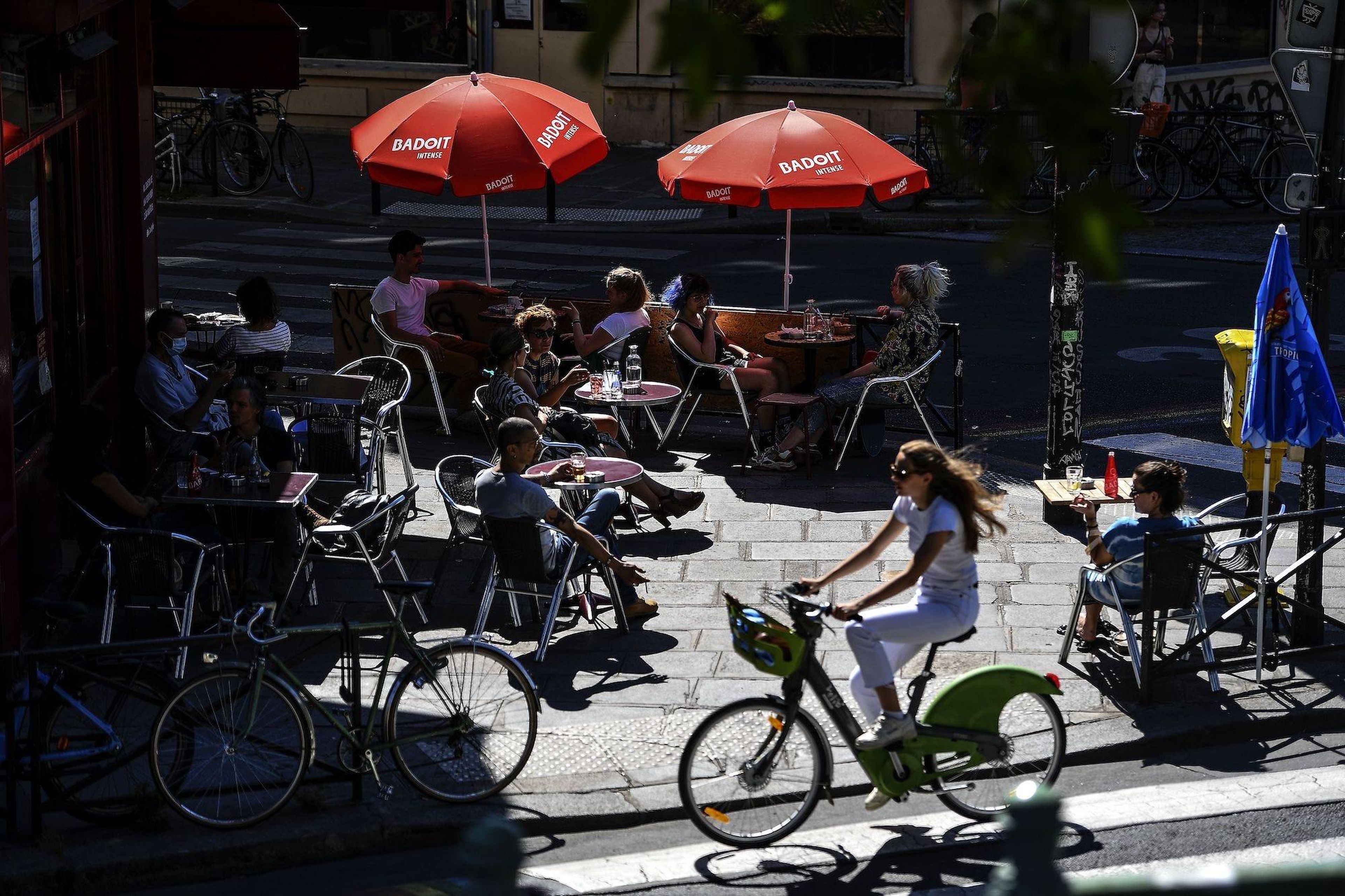 People have drinks at the terrasse of a cafe along the Canal Saint-Martin on a warm and sunny afternoon during a heatwave in Paris, on June 23, 2020 as France eases lockdown measures taken to curb the spread of the Covid-19 pandemic.
