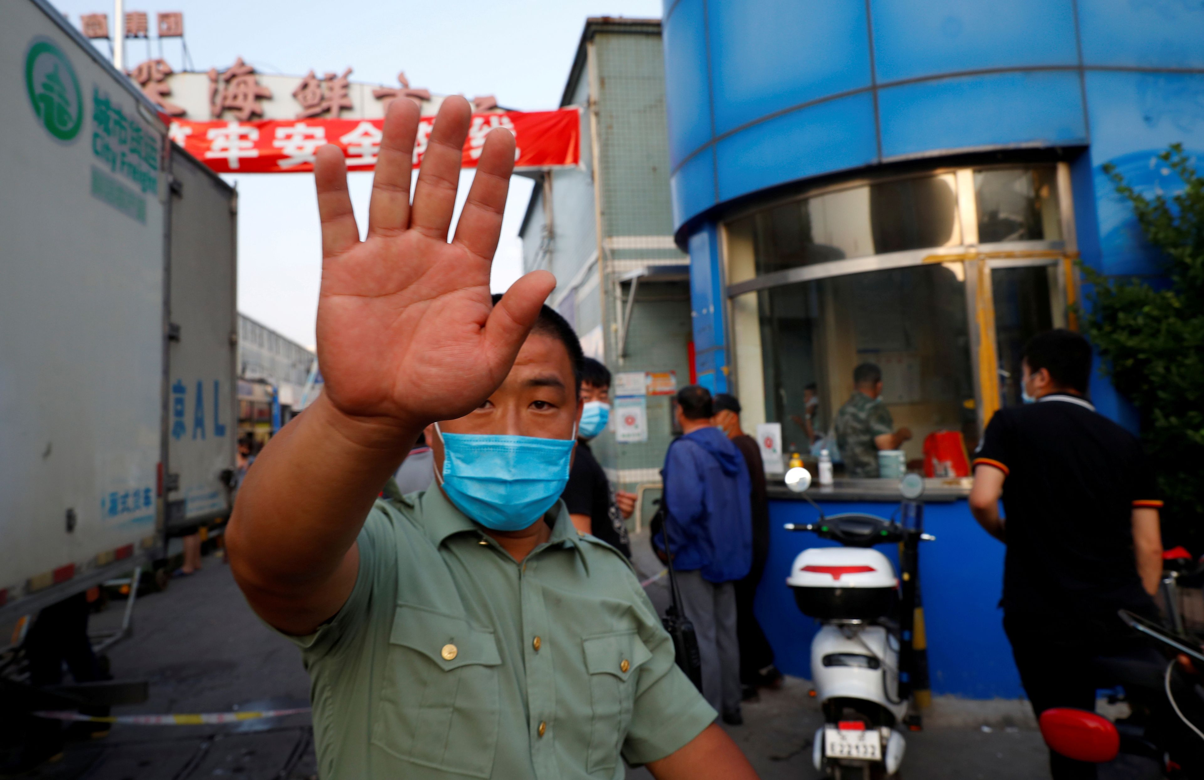 Un guardia de seguridad intenta bloquear una cámara fuera del mercado de mariscos Jingshen, cerrado tras detectar nuevas infecciones por coronavirus, en Beijing, China.