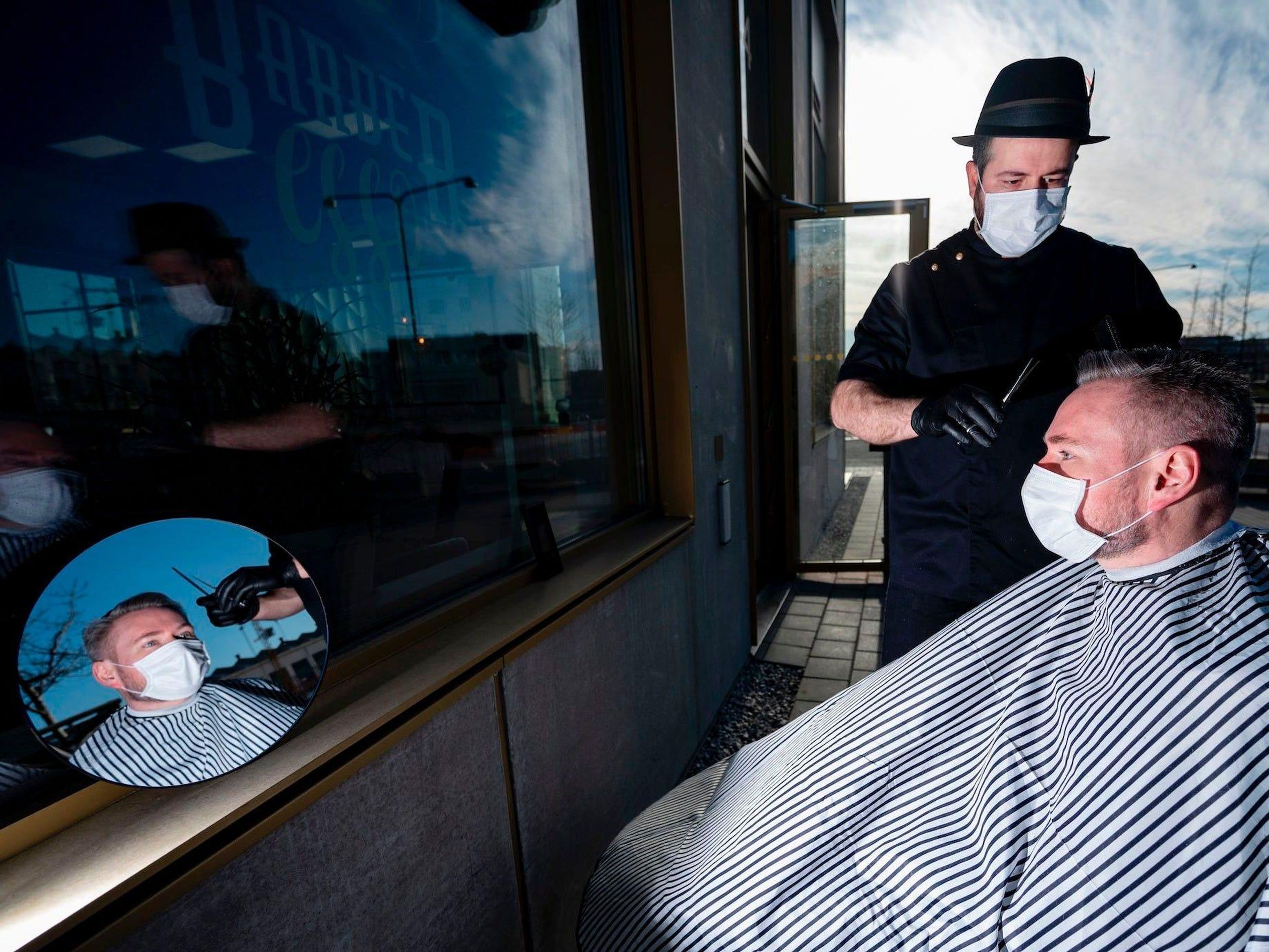 El peluquero Abed Khankan le corta el pelo a un cliente al aire libre como precaución en medio de la nueva pandemia de coronavirus, 17 de abril de 2020 en Malmo, Suecia.