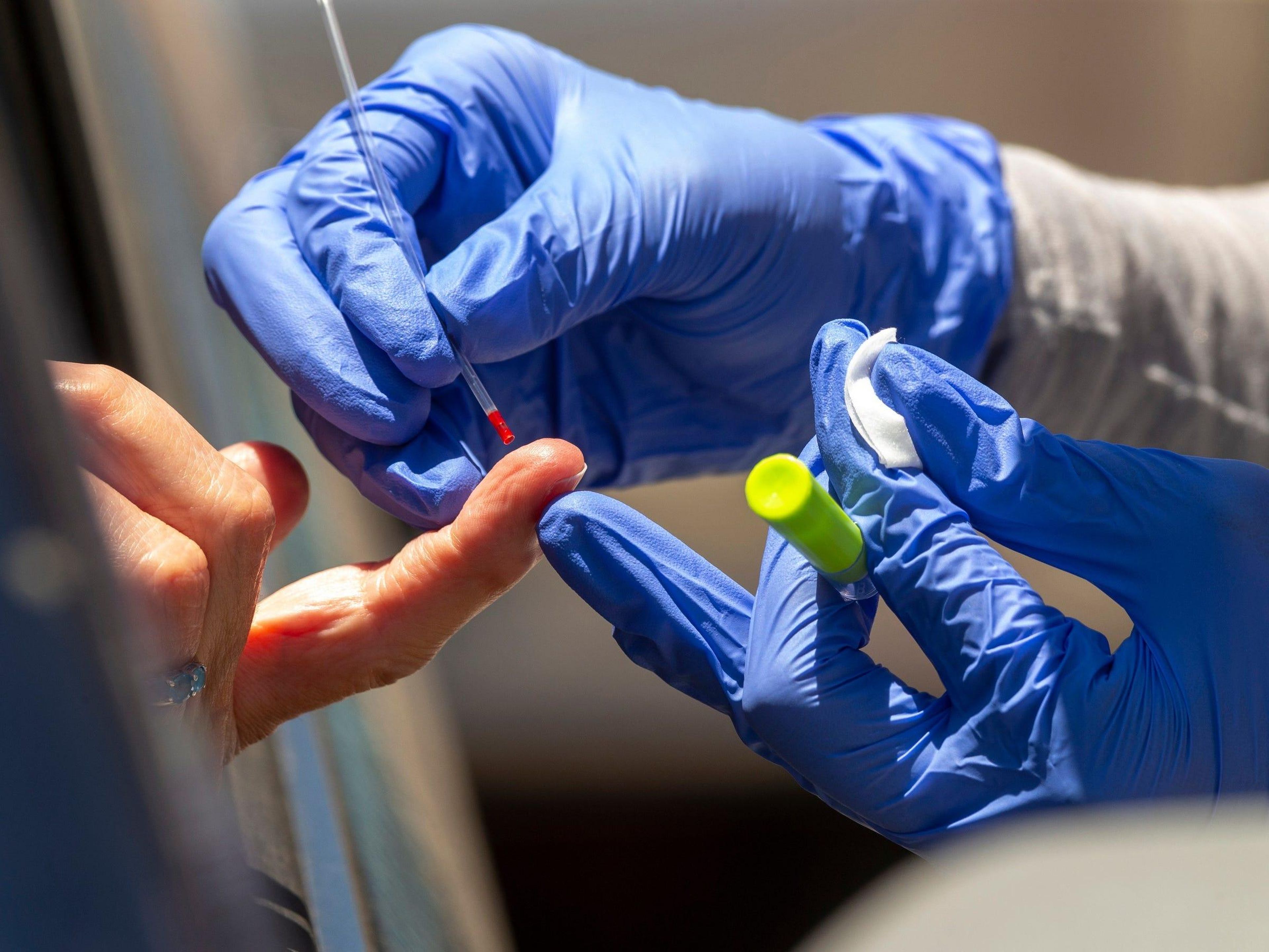 A health worker takes a blood sample for a COVID-19 antibody test in Los Angeles, California, May 20, 2020.