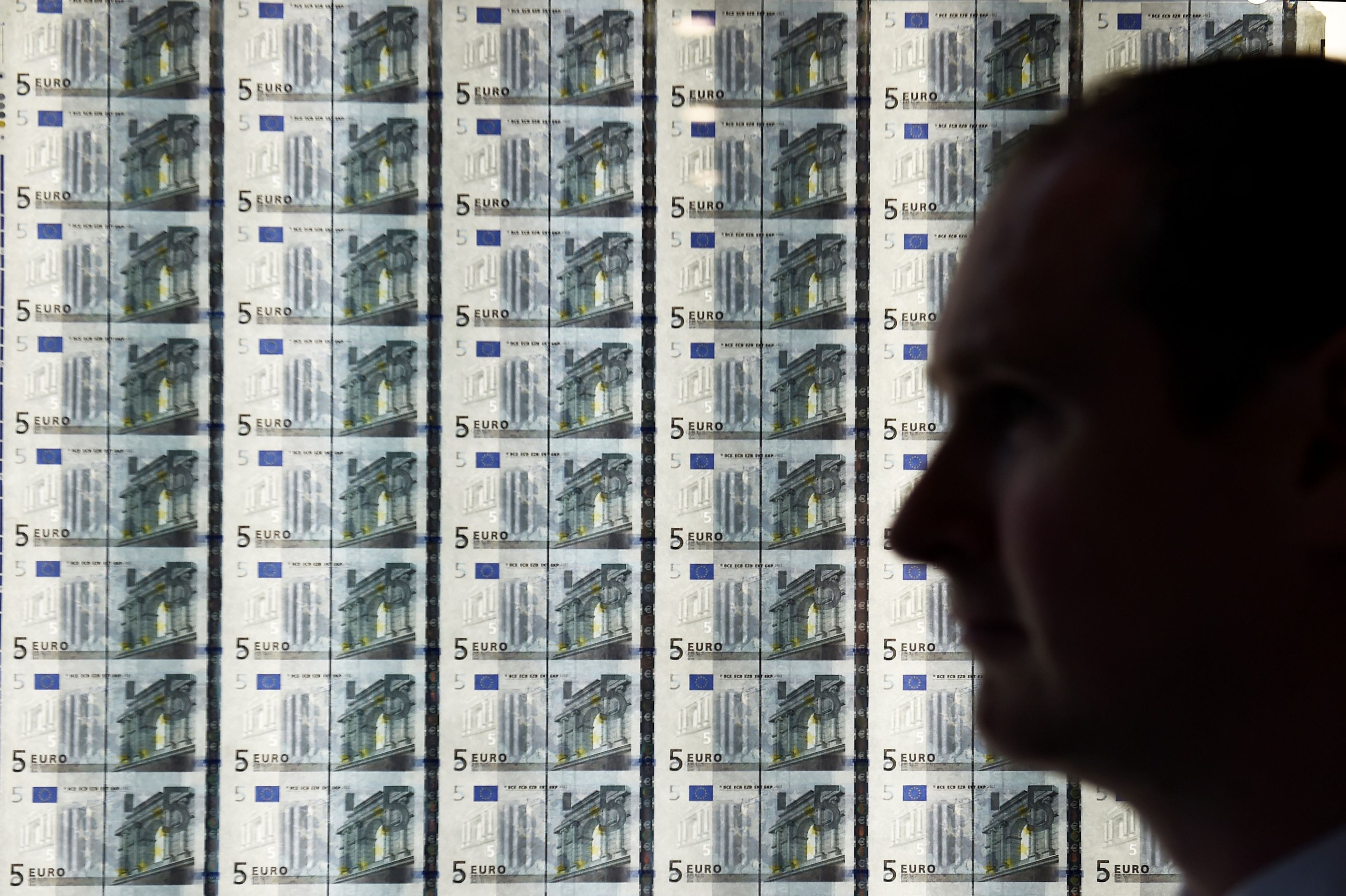 Un hombre delante de una plancha de billetes de euro