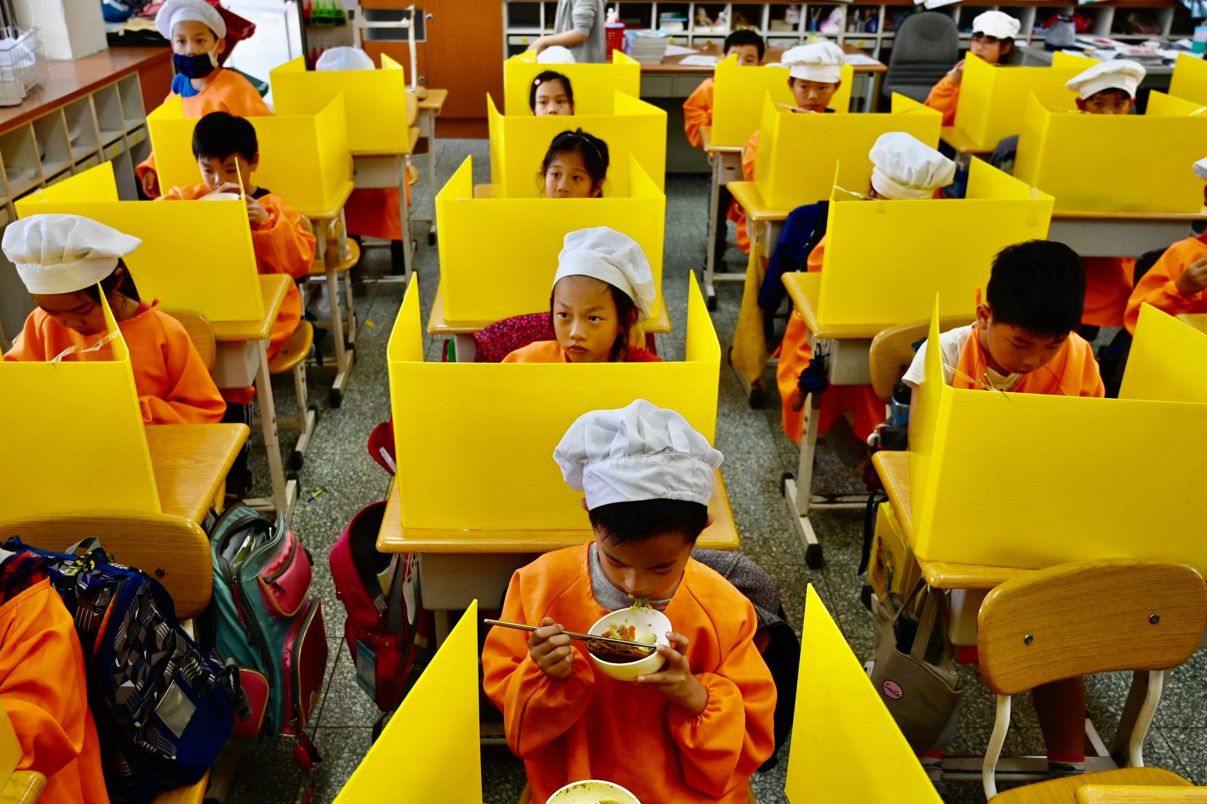 Students eat their lunch on desks with plastic partitions as a preventive measure to curb the spread of the COVID-19 coronavirus at Dajia Elementary School in Taipei on April 29, 2020.