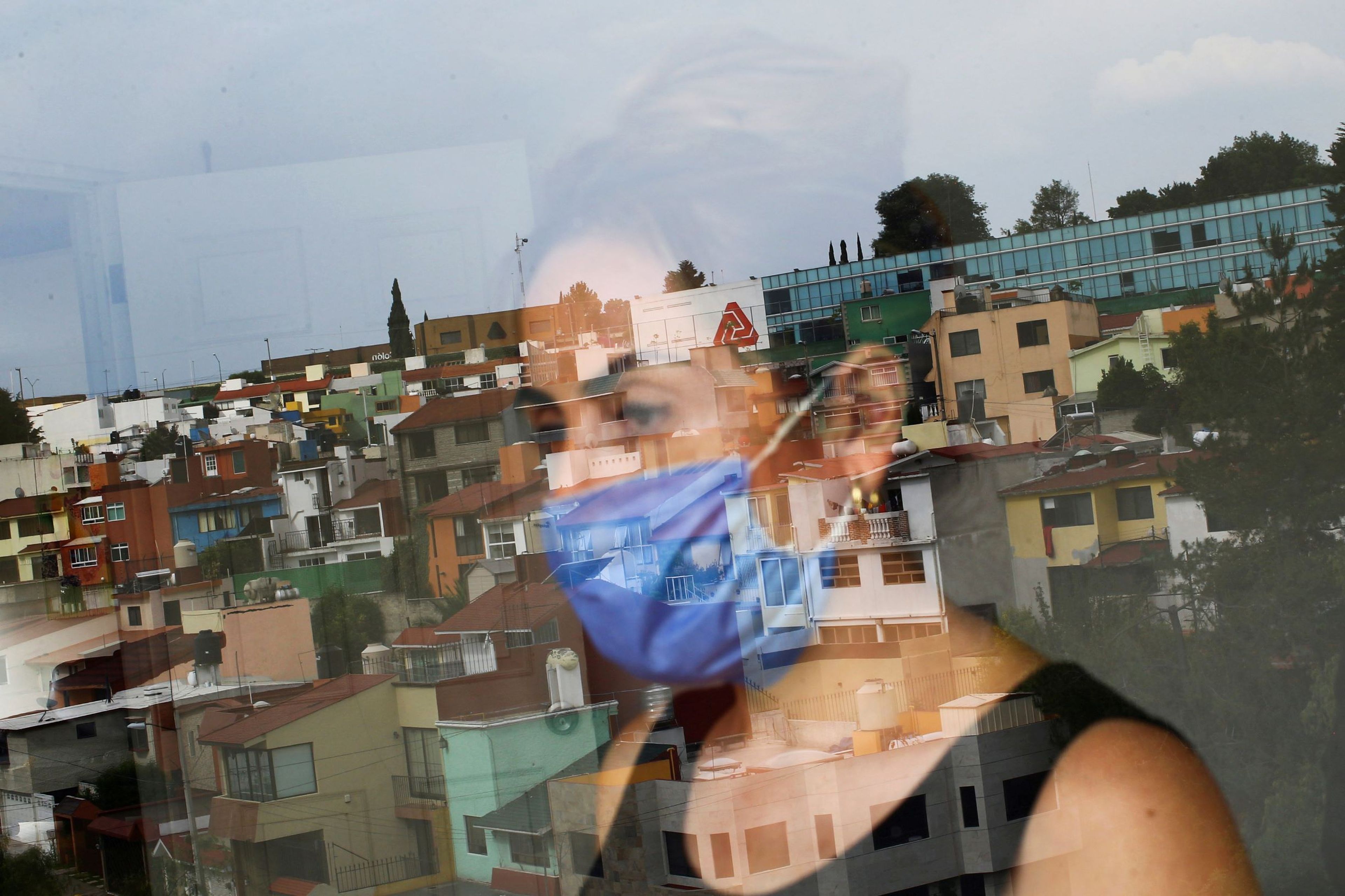 Una mujer con mascarilla mira por la ventana durante la crisis del coronavirus en México.