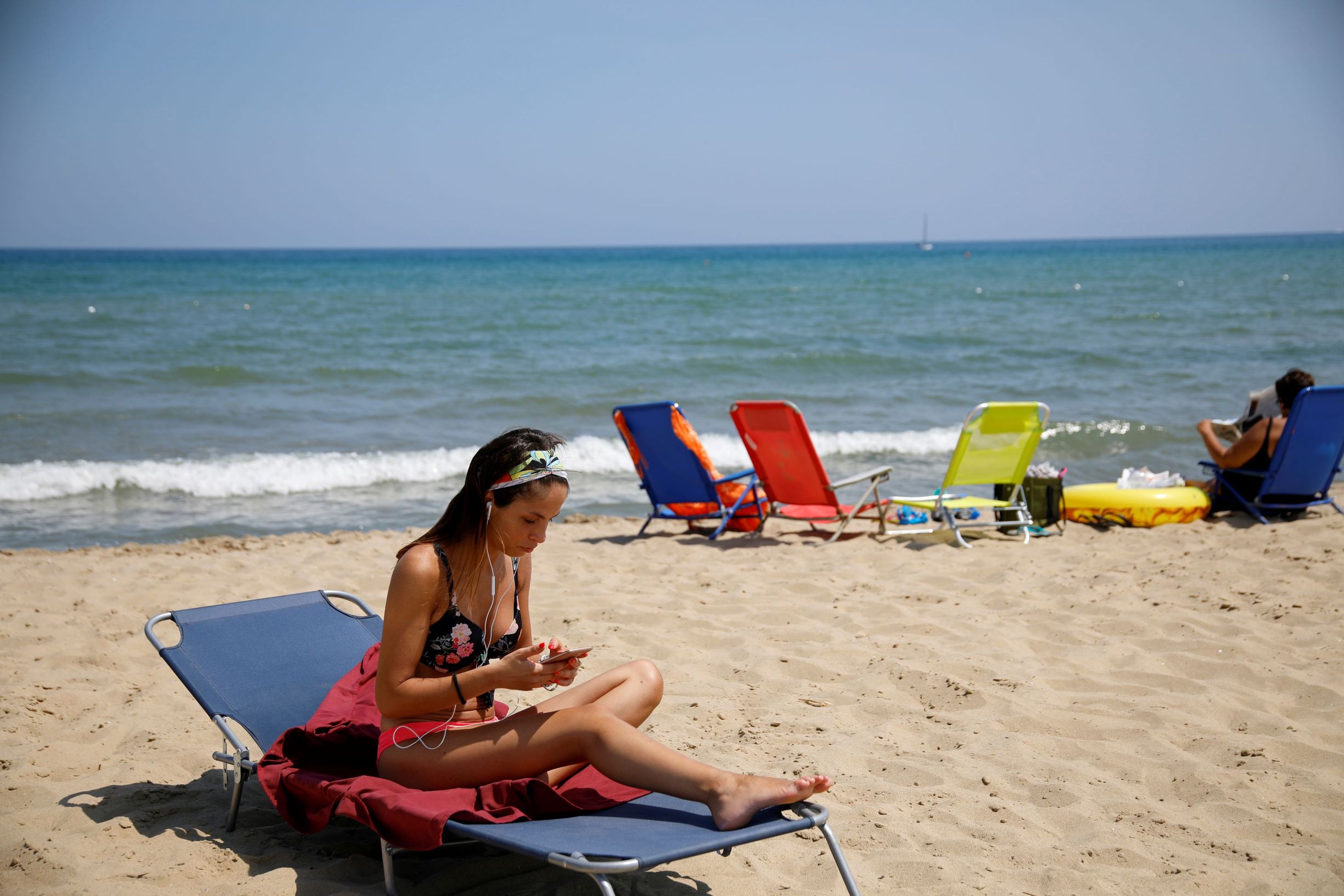 Una mujer utilizando su móvil en la playa, en Italia.
