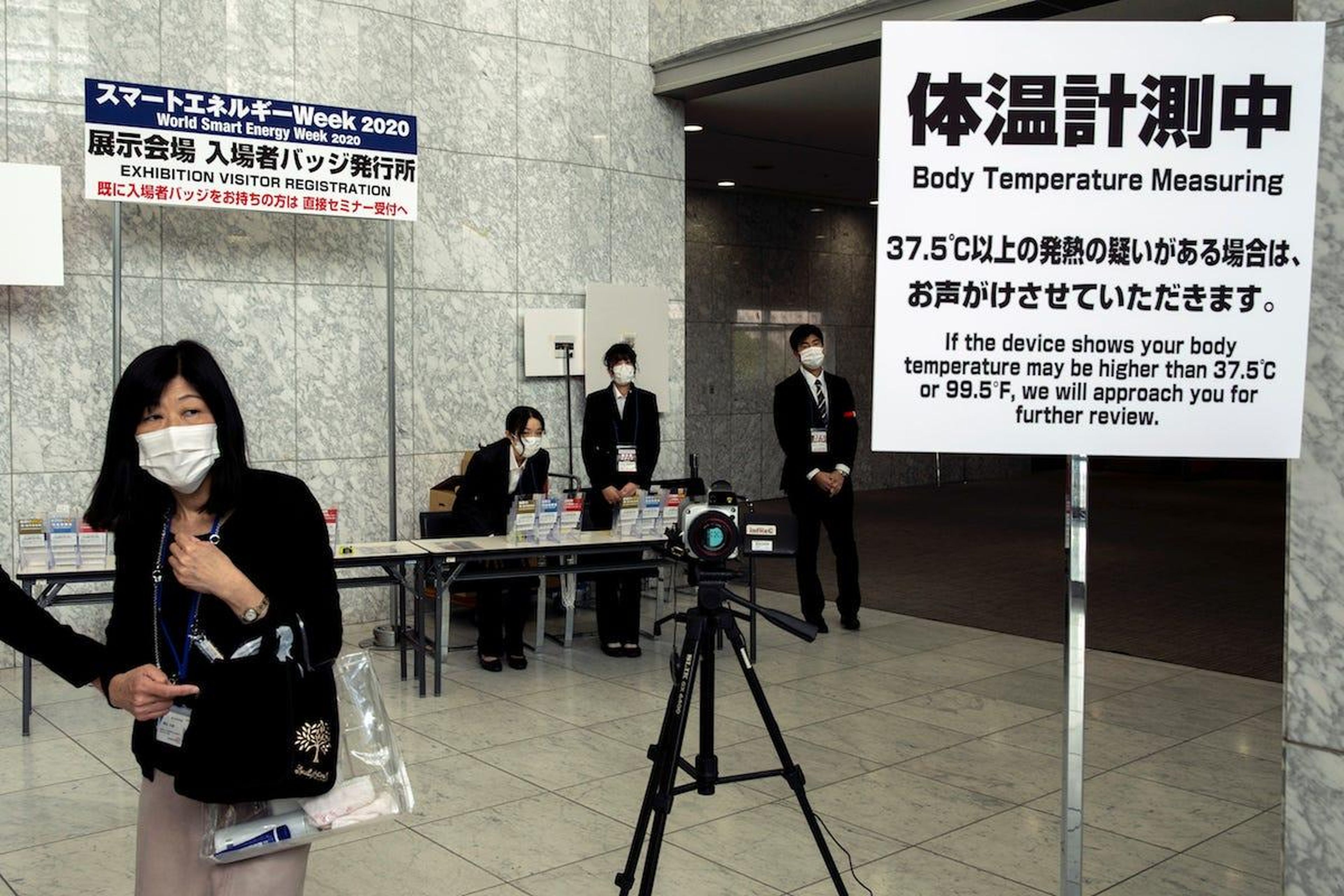 Personas con mascarillas cerca de una máquina que mide la temperatura corporal en un salón de convenciones en Tokio, Japón, el 27 de febrero de 2020.