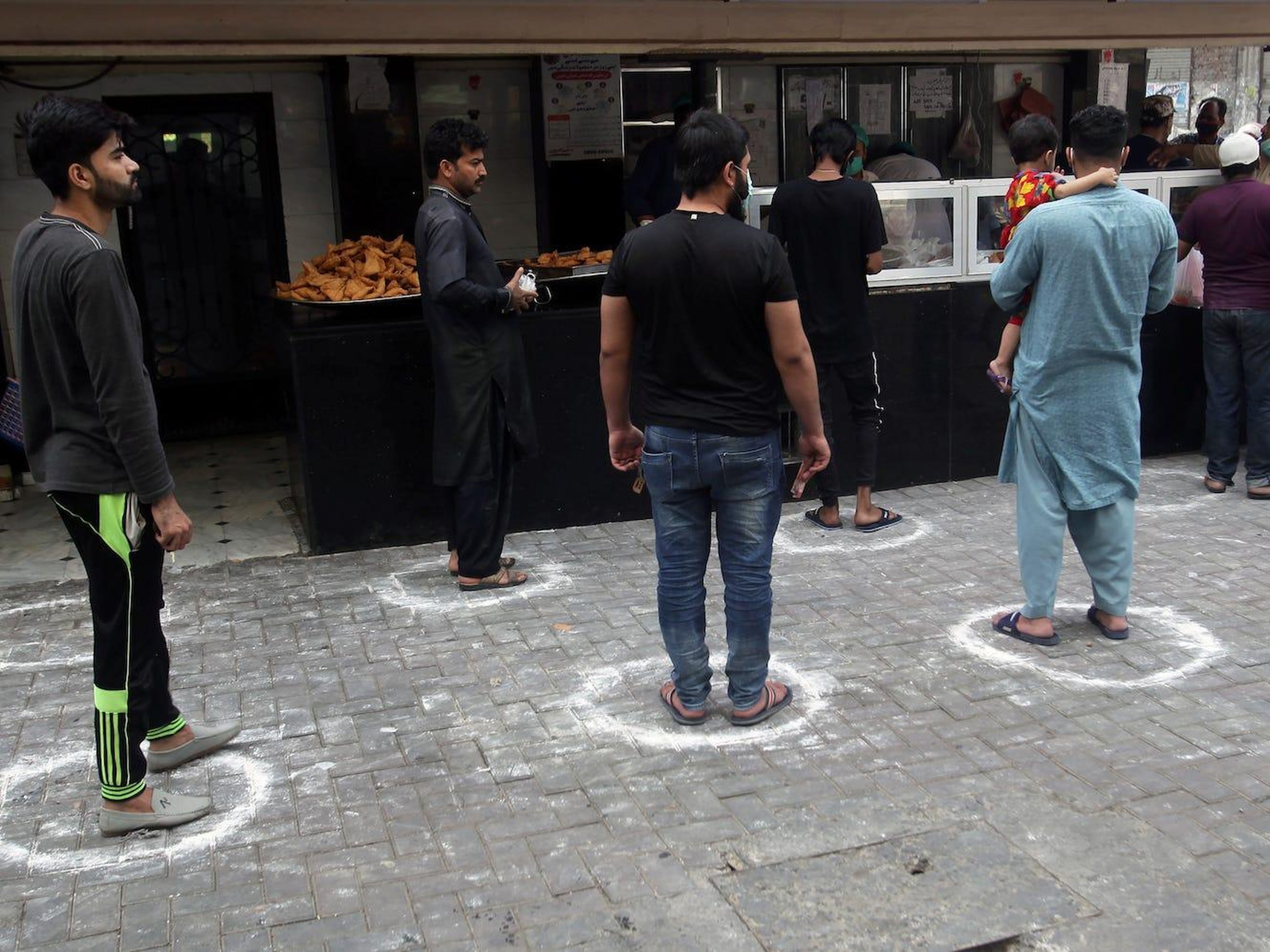 Las personas se paran en las marcas manteniendo una distancia segura, mientras compran comida para romper el ayuno, ya que el mes de ayuno musulmán del Ramadán comienza en Lahore, Pakistán, el 25 de abril de 2020.