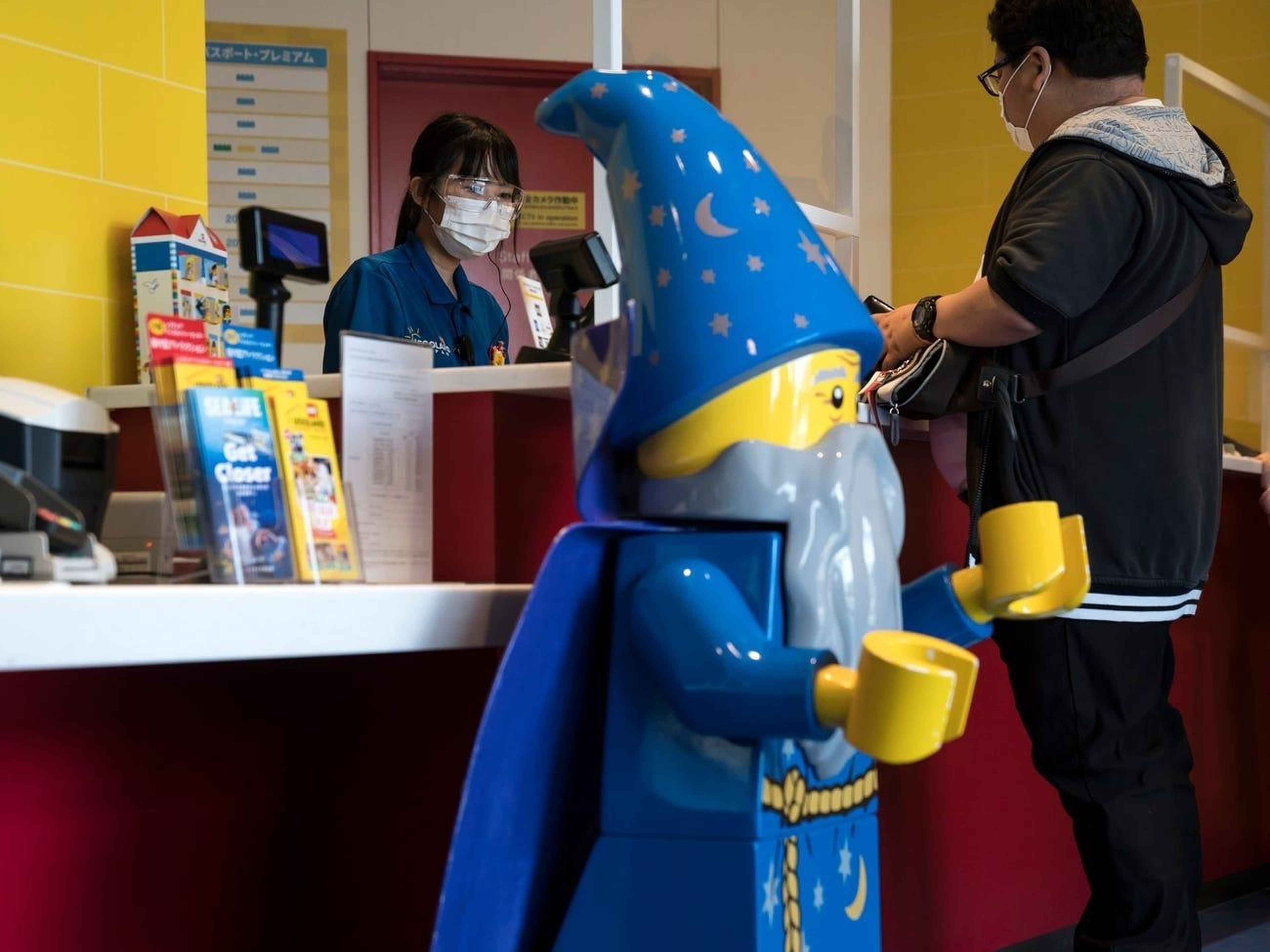Una empleada detrás de láminas de plástico en la taquilla de Legoland.