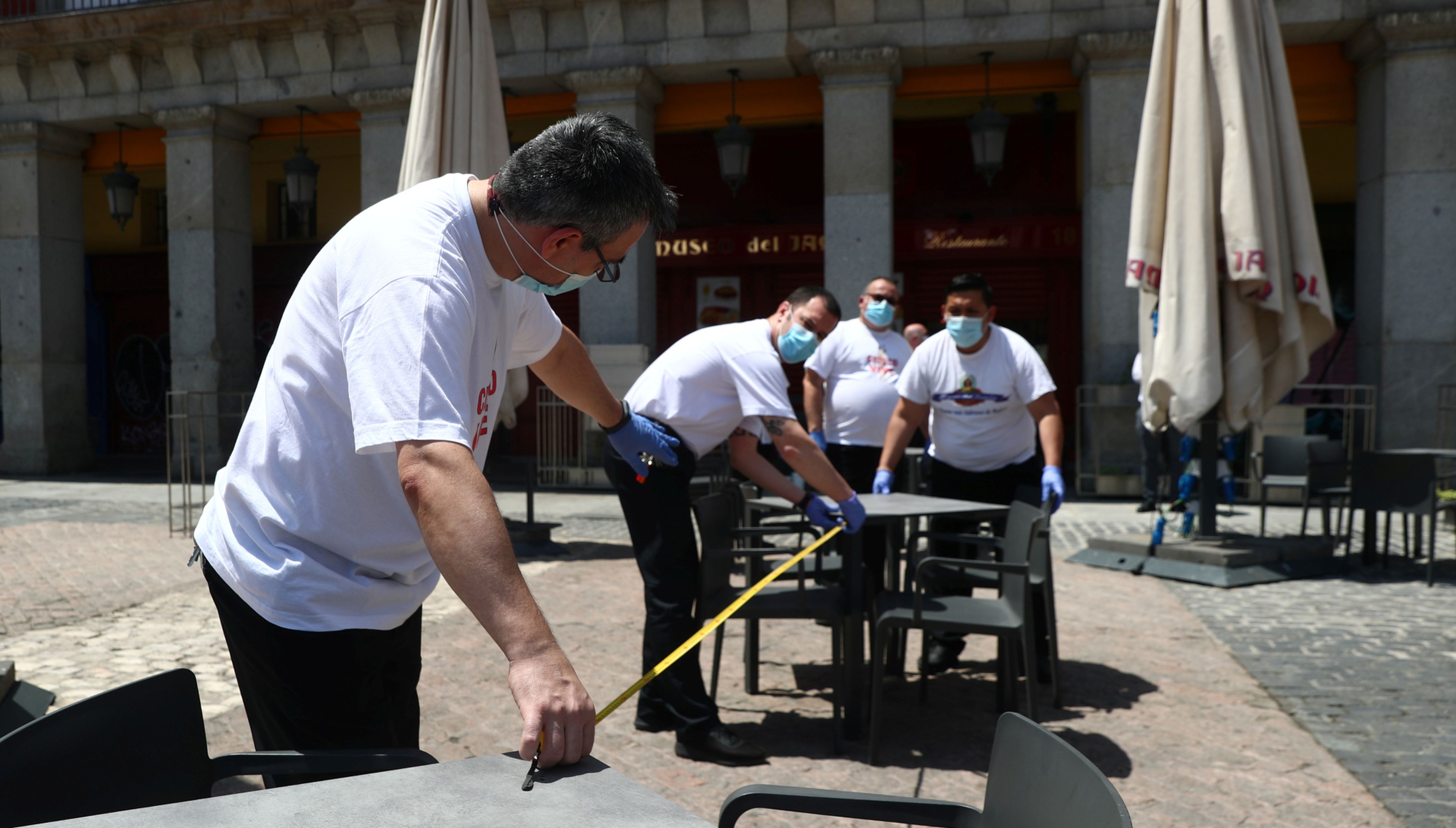 Trabajadores de un bar de la Plaza Mayor de Madrid miden la distancia entre mesas al reabrir tras el coronavirus