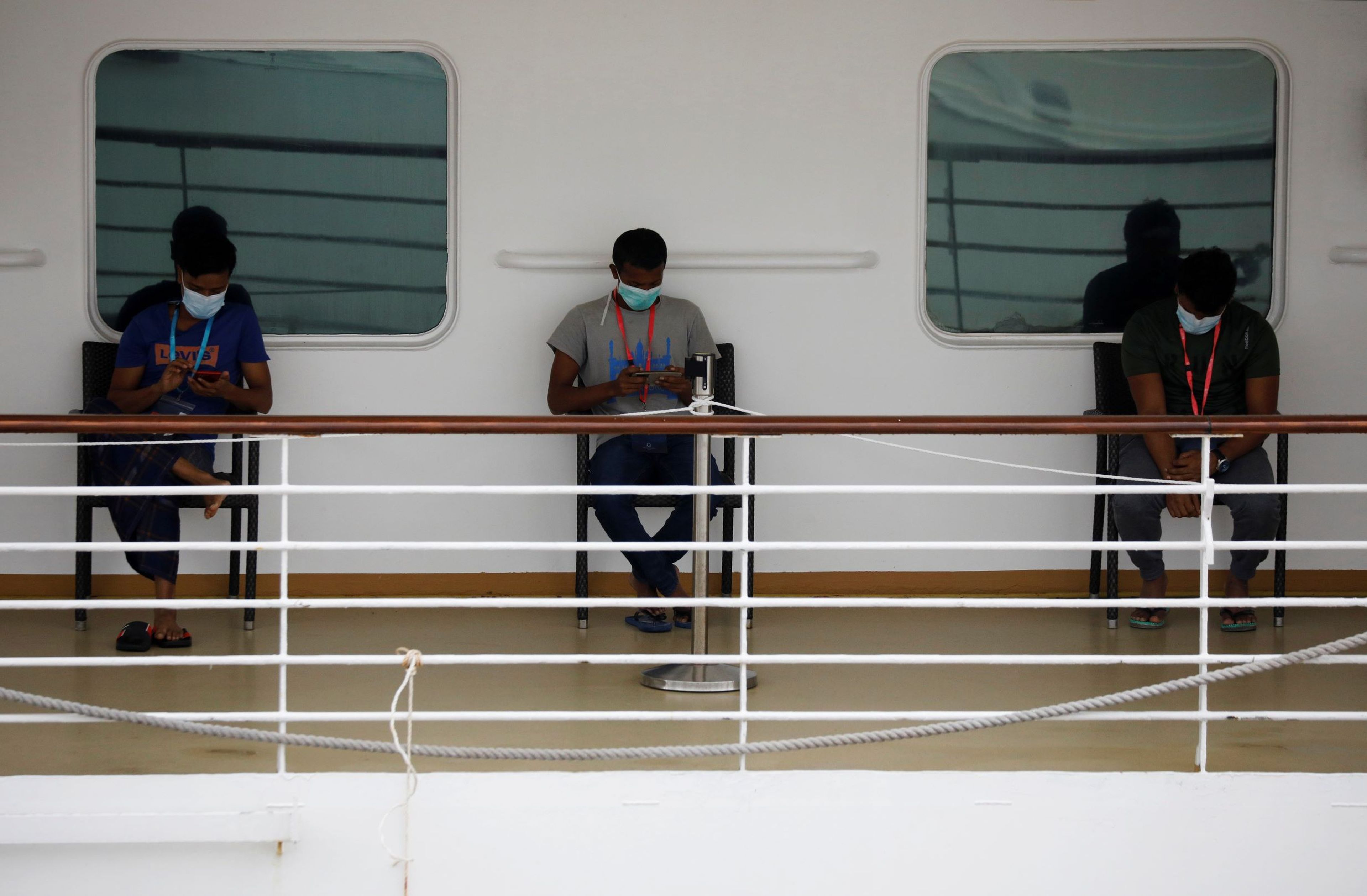 Tres personas con mascarillas en el crucero SuperStar Gemini en Singapur durante el coronavirus.
