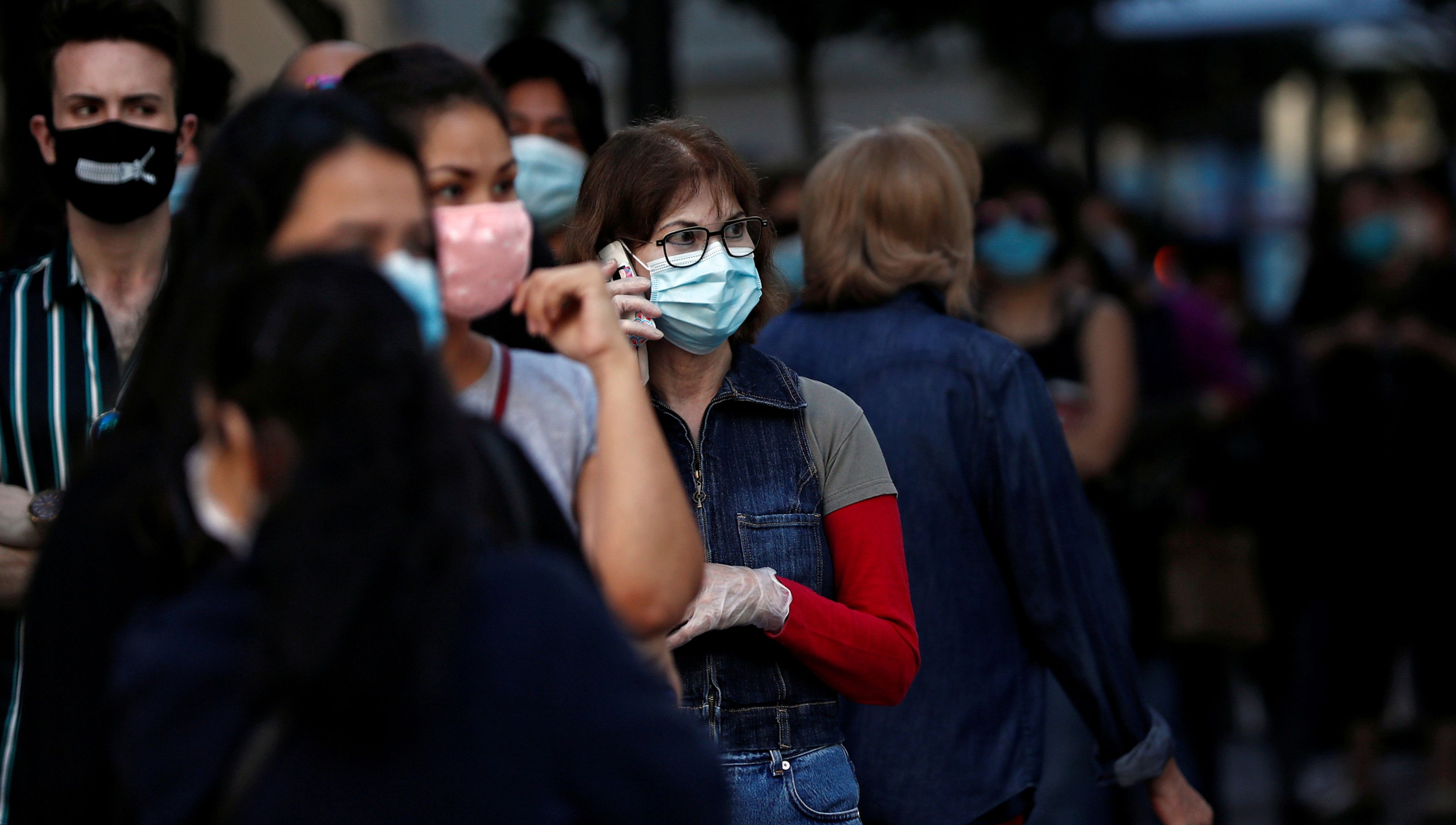 Varias personas con mascarilla hacen cola para entrar a una tienda Primark de Madrid