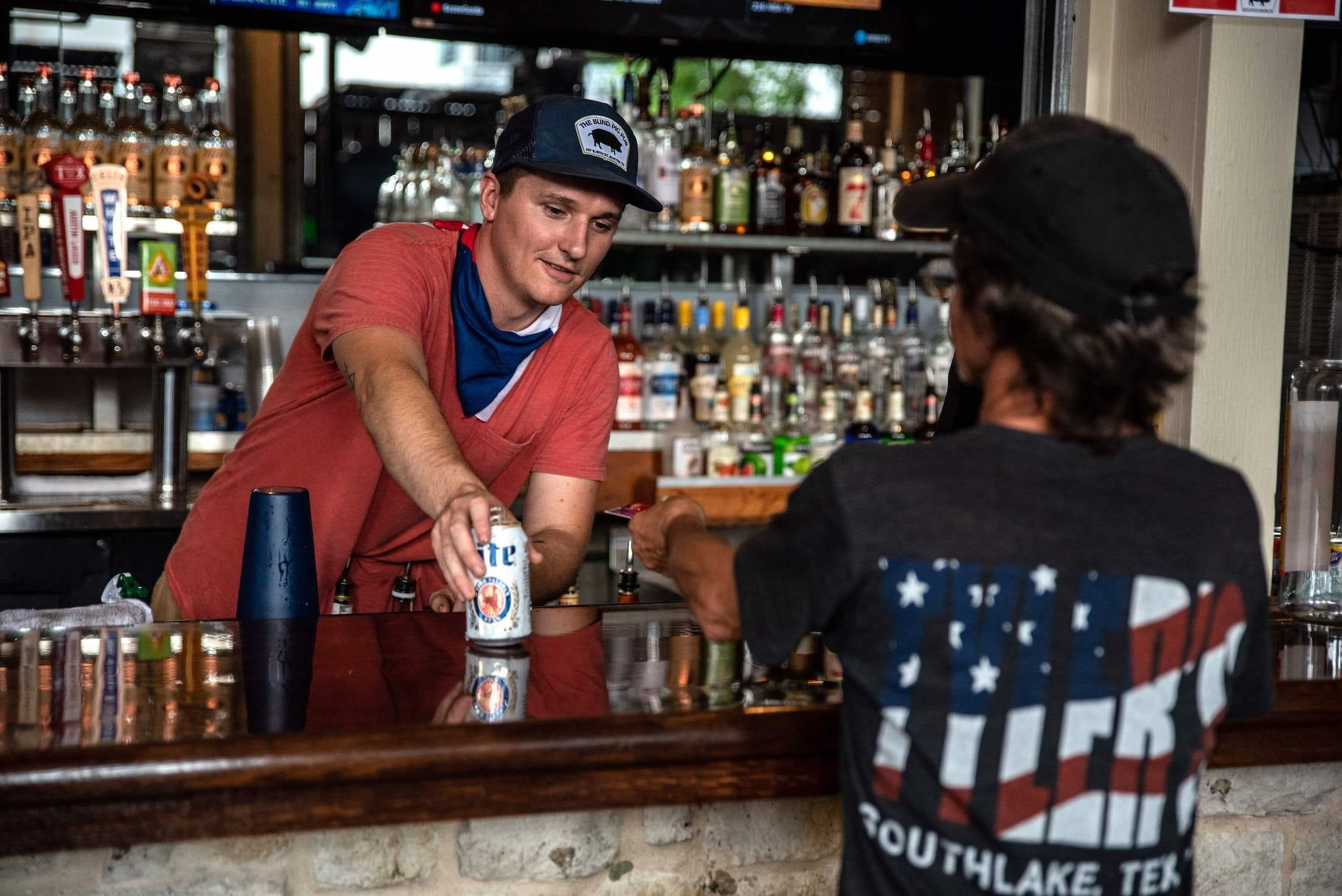 Un camarero sirve una bebida a un cliente en un bar de Austin, Texas, el 22 de mayo de 2020, el día en que los bares de la ciudad reabrieron del cierre por coronavirus.