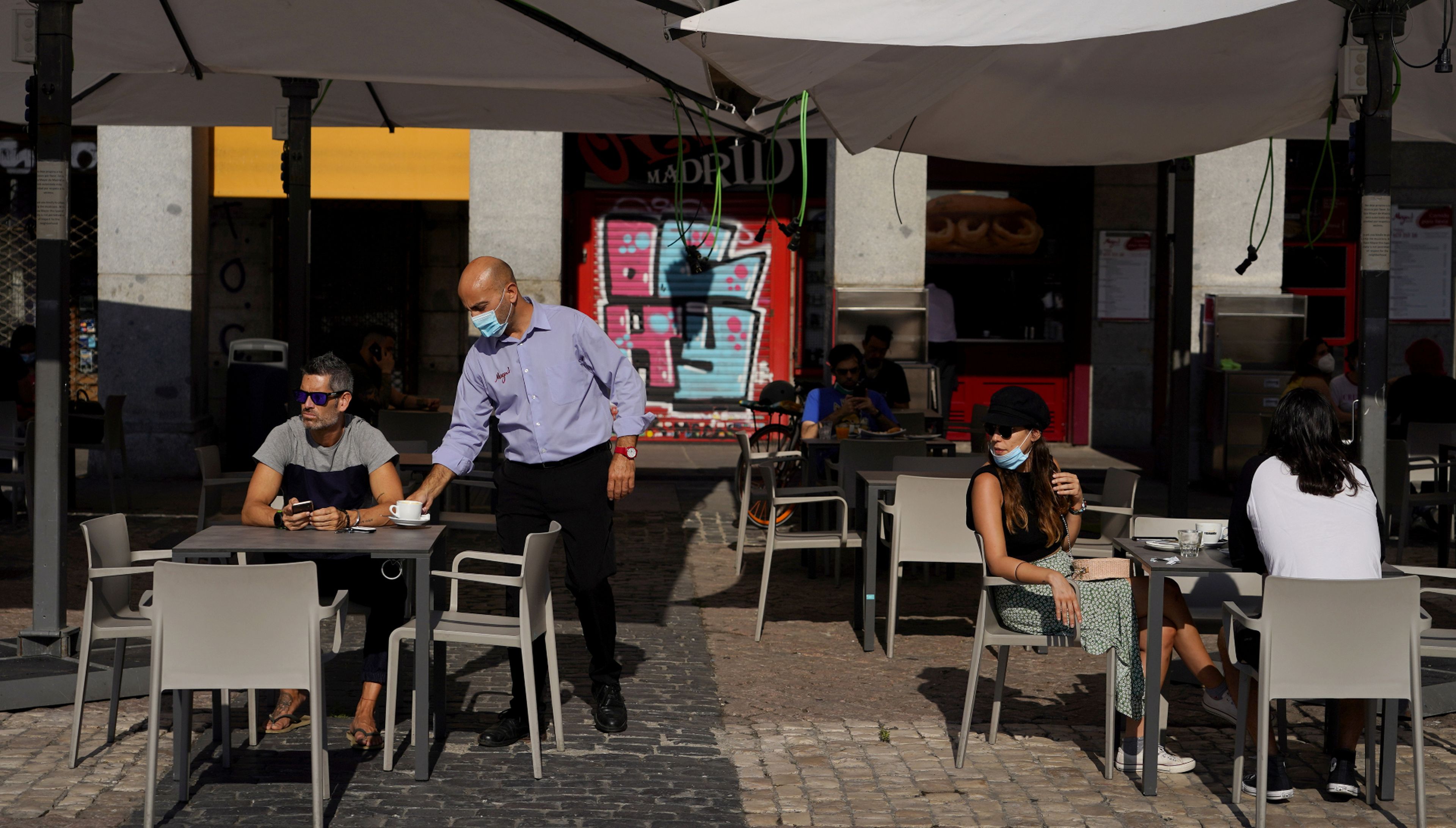 Un camarero con mascarilla sirve un café en una terraza de Madrid