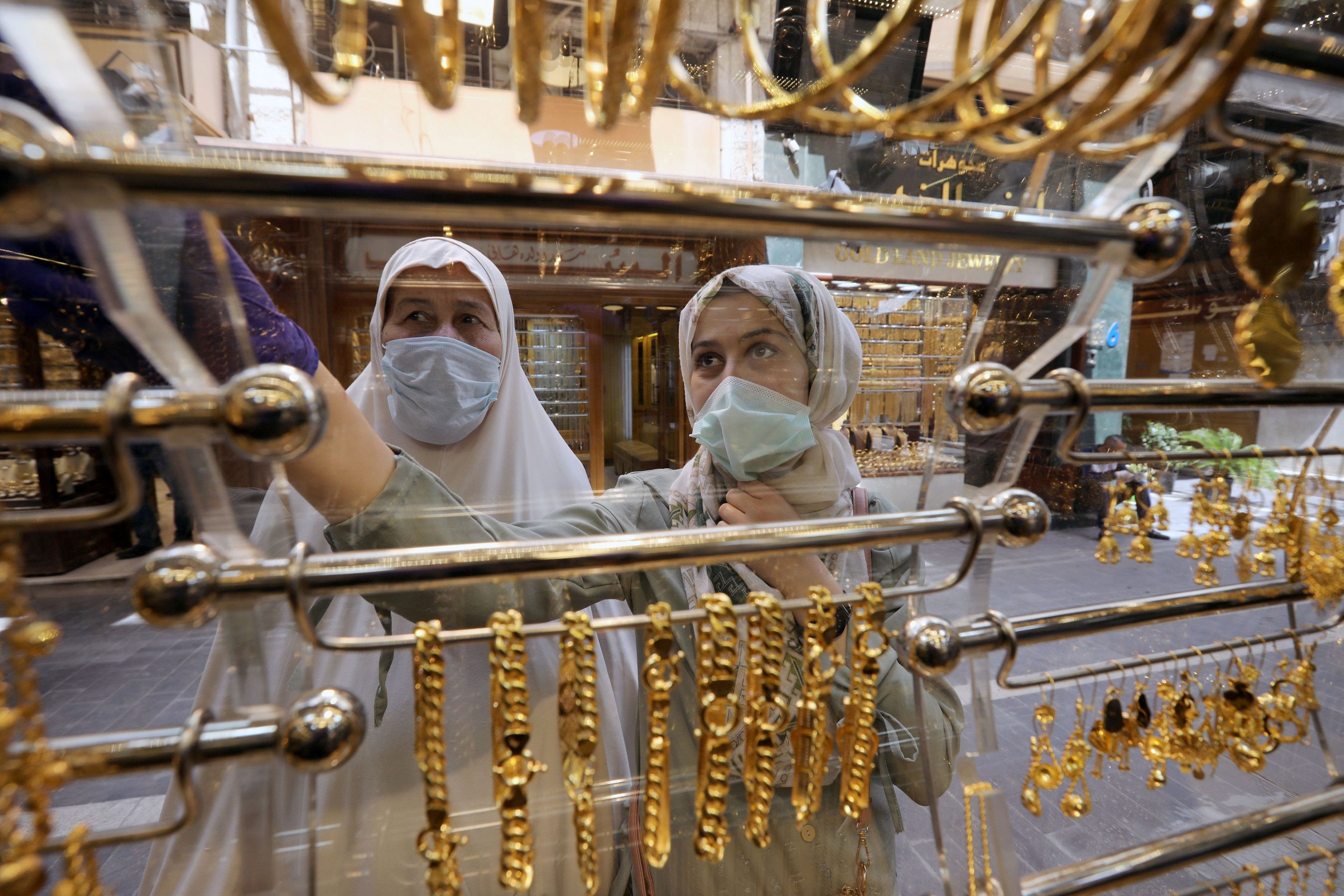 Dos mujeres con mascarilla mirando joyas de oro