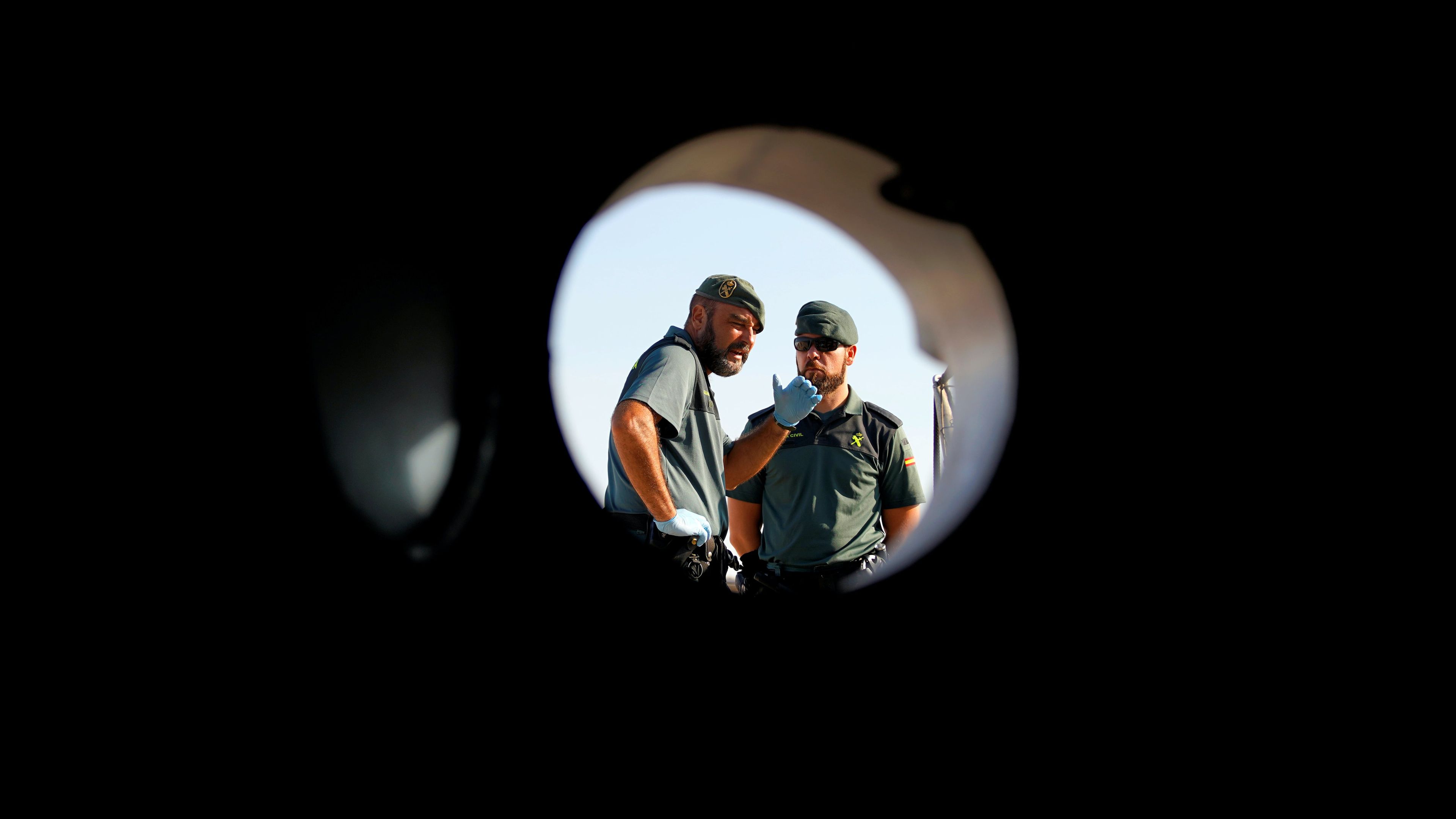 Dos guardias civiles miran a través de una de las ventanas del barco de Proactiva Open Arms.