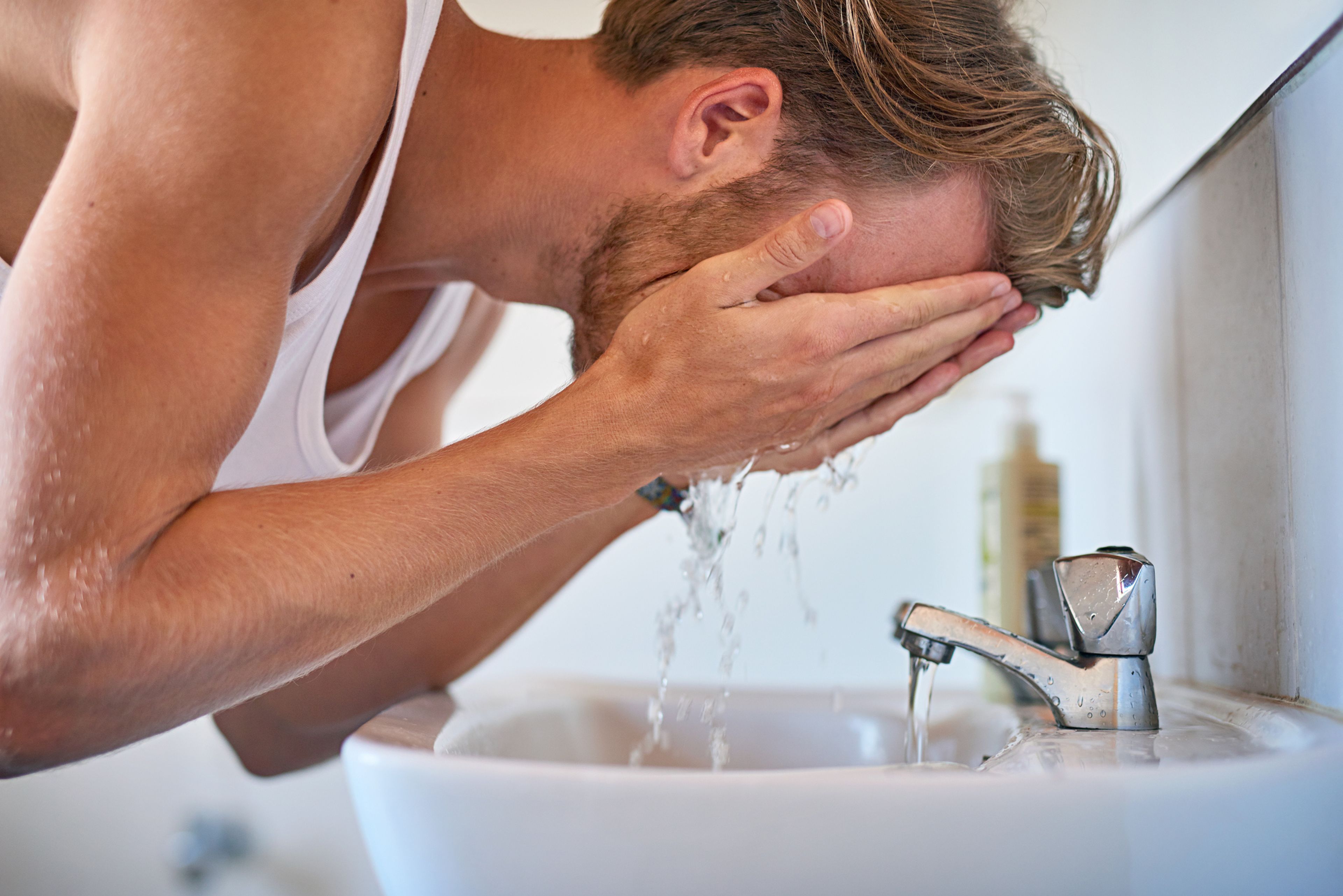 Un hombre se lava la cara.