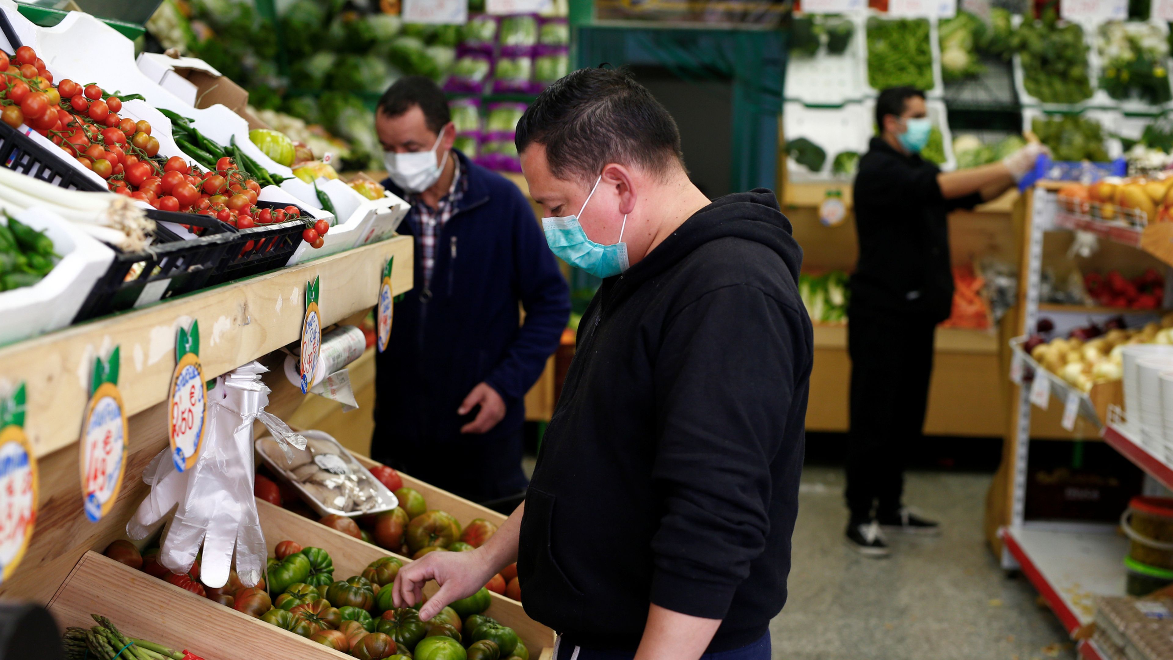 Un hombre con mascarilla compra verduras en un mercado