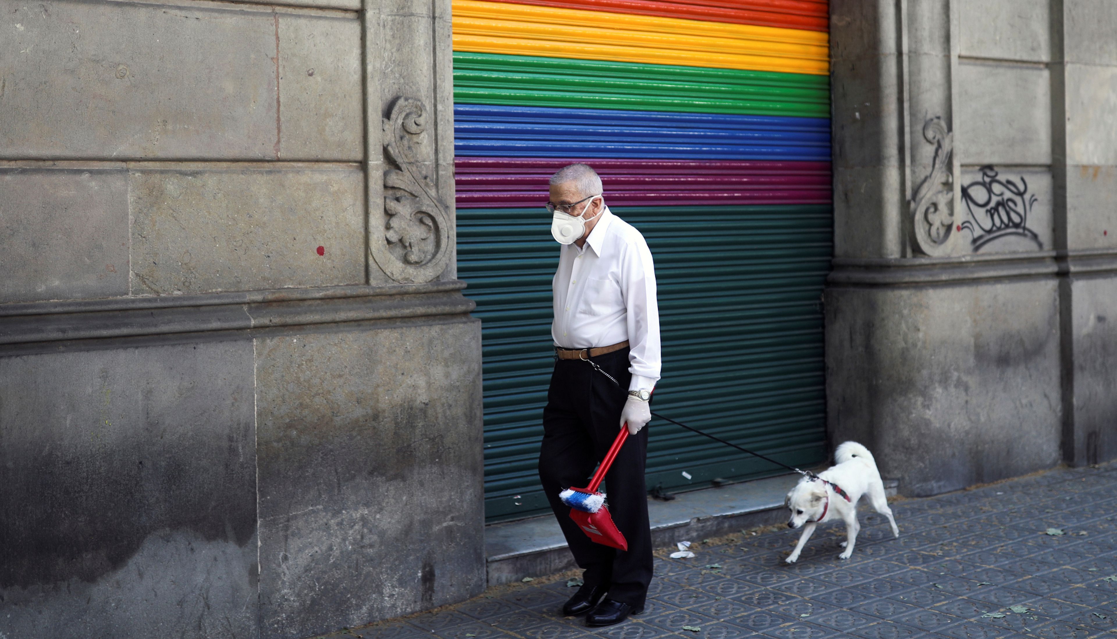 Un jubilado con mascarilla pasea a su perro en Barcelona