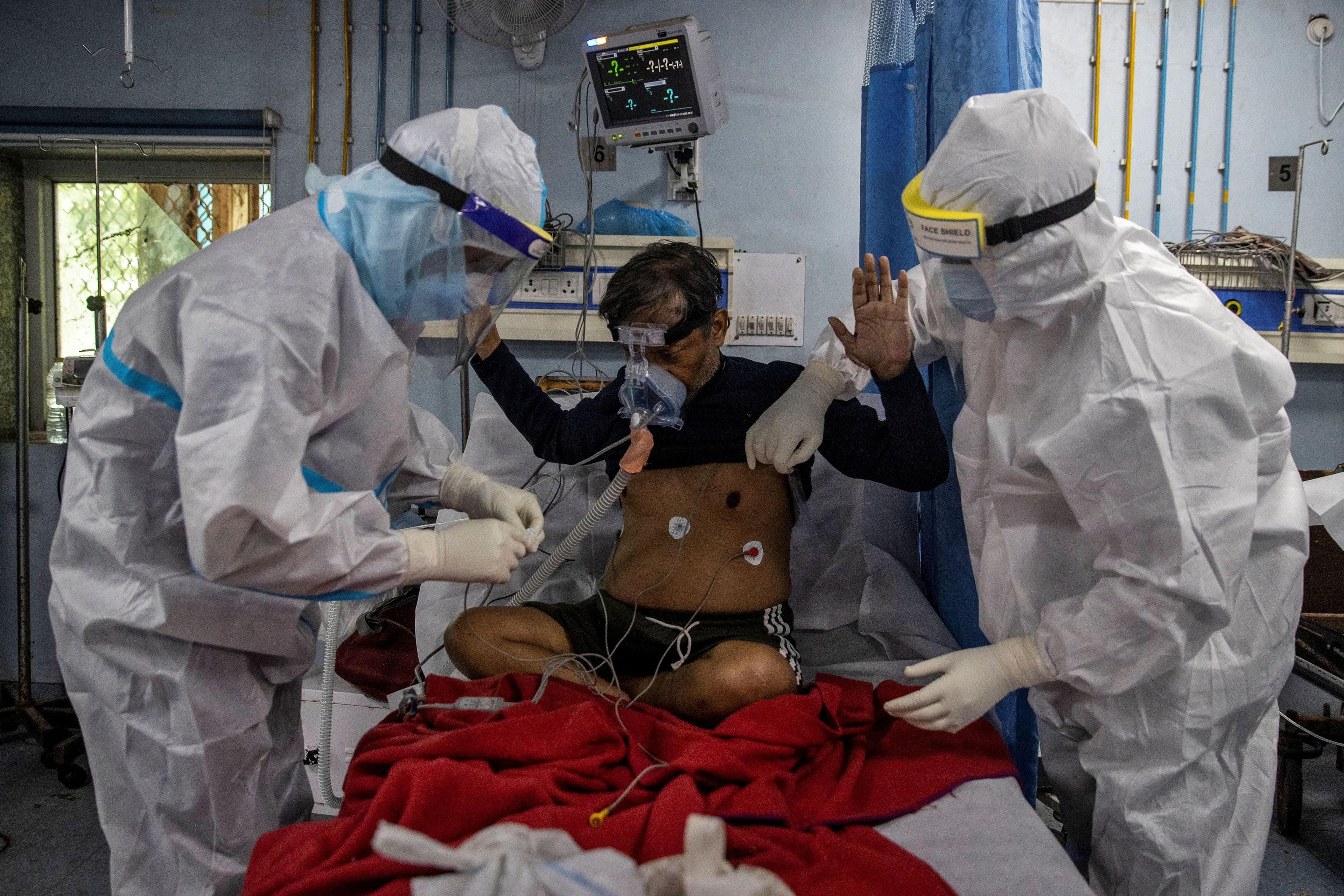Unos médicos vestidos con trajes de protección examinan a un enfermo de COVID-19