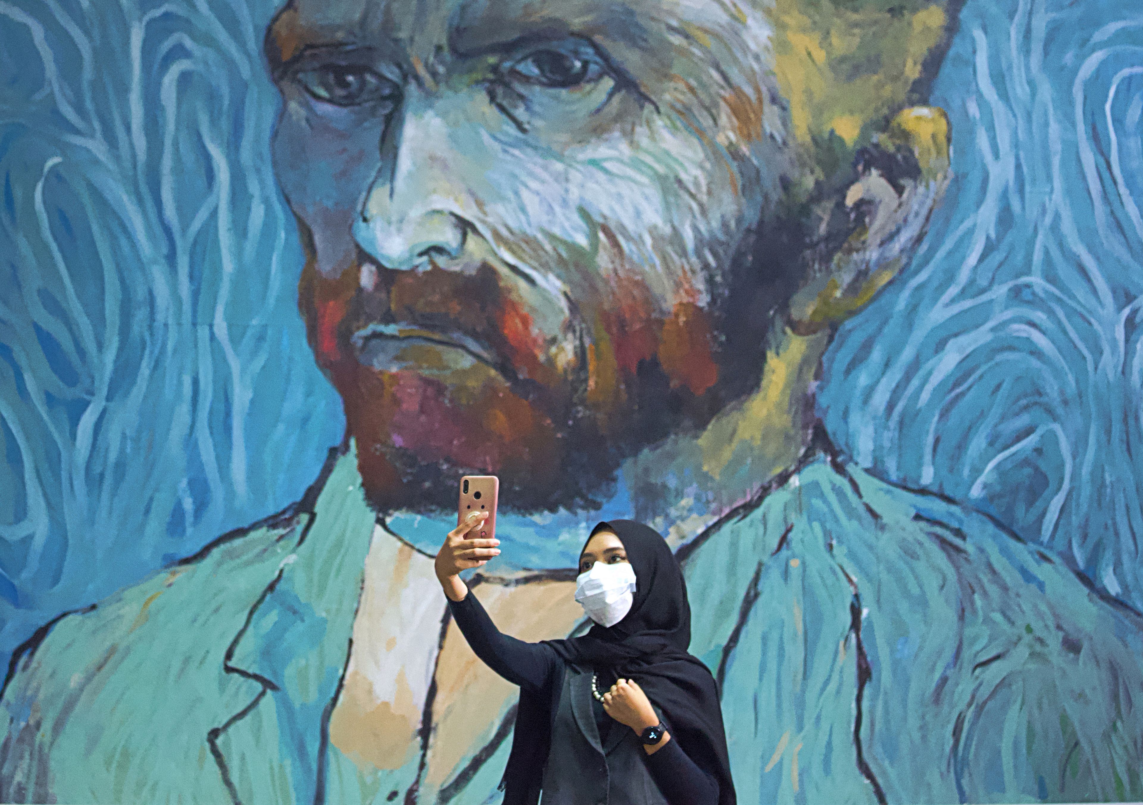 Una mujer se hace un selfie con un mural en medio de la pandemia de coronavirus