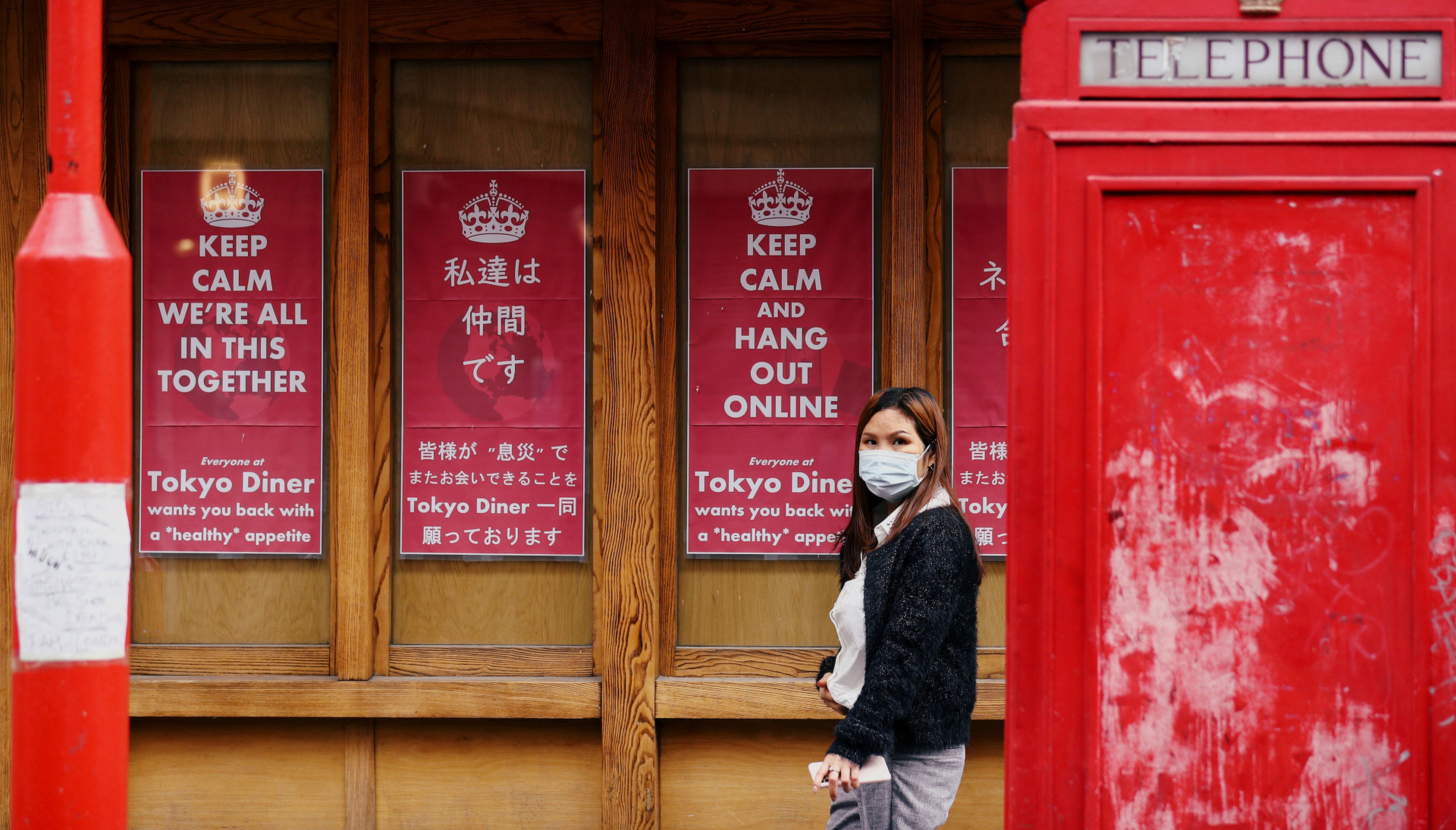 Una mujer con mascarilla pasa ante un negocio cerrado por coronavirus en Londres (Reino Unido)