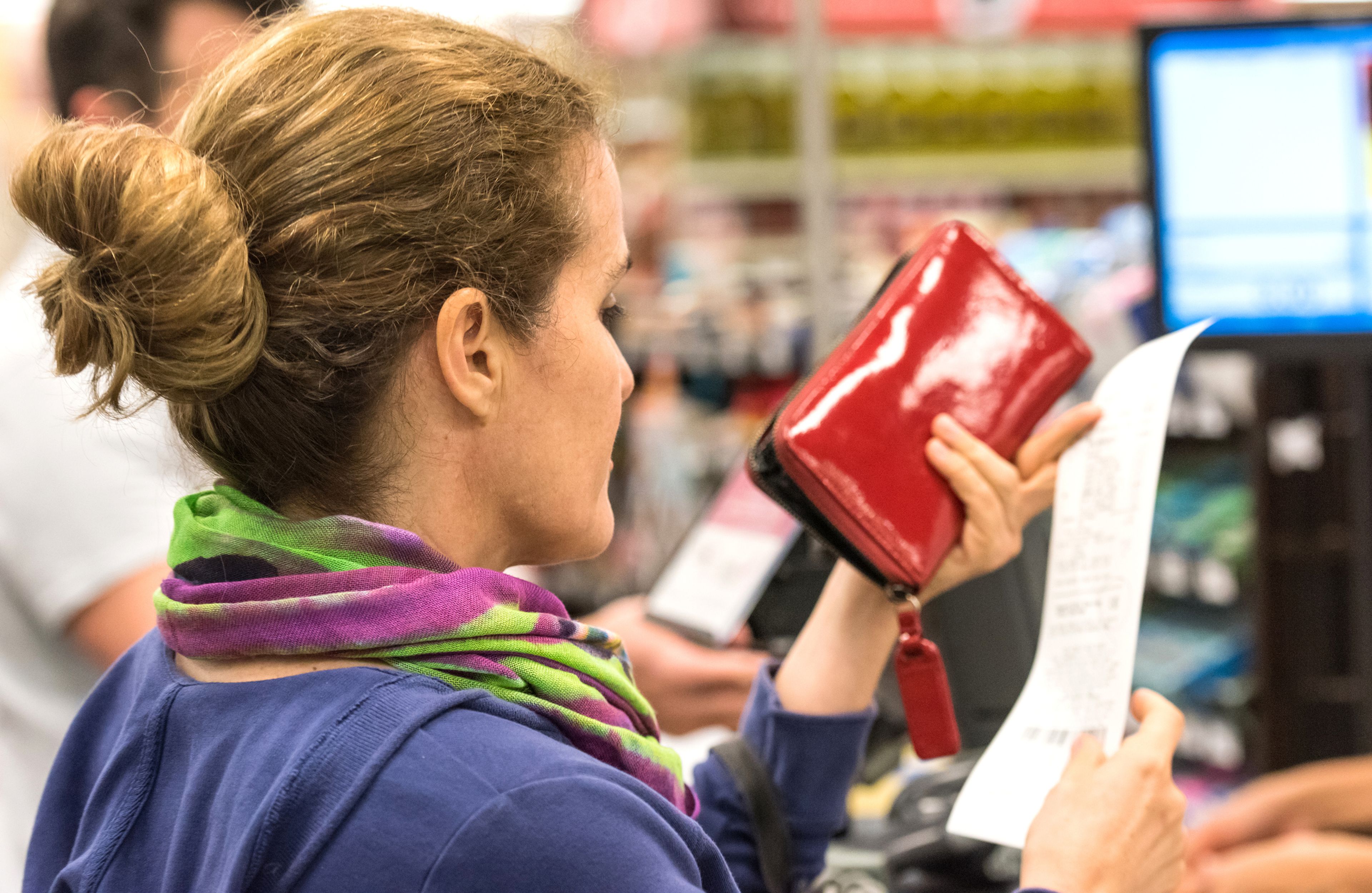 mujer revisa ticket de compra en supermercado