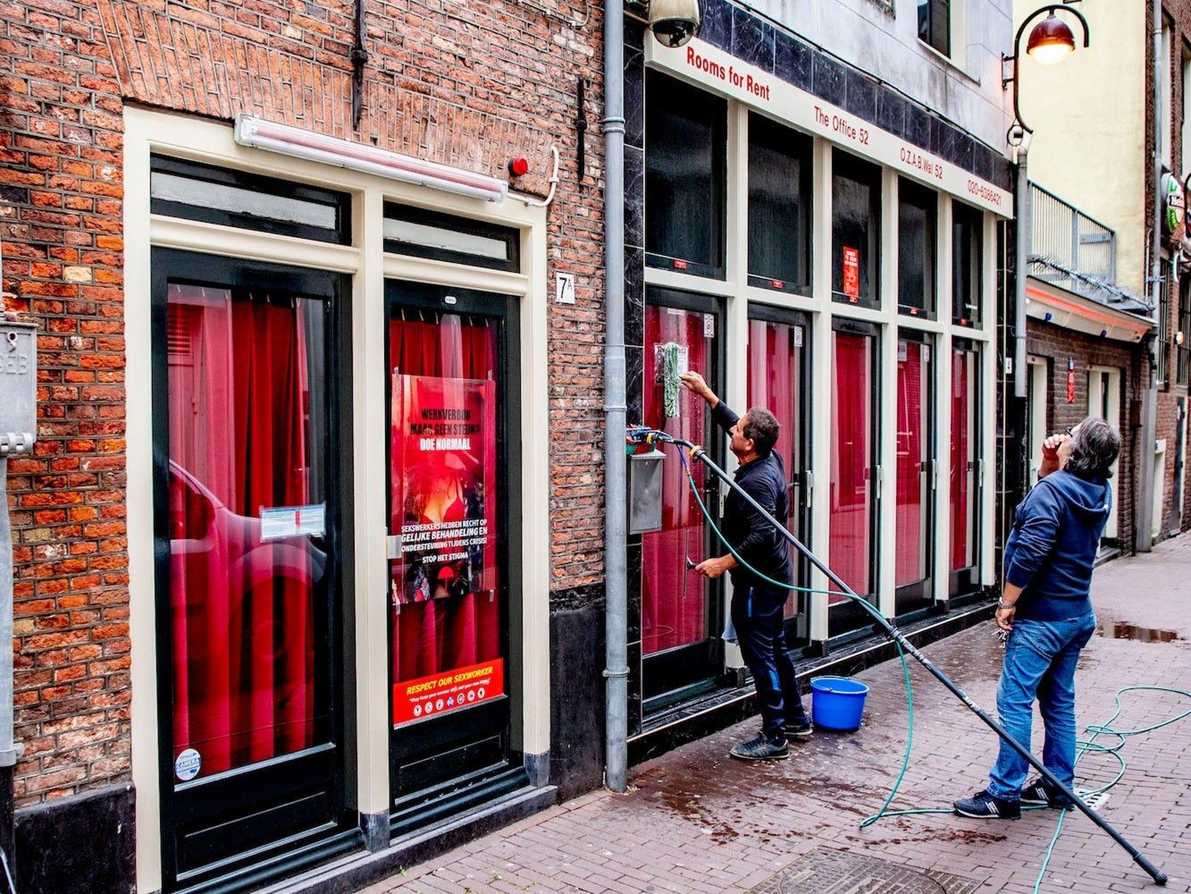 Trabajadores limpiando ventanas de vidrio en un edificio del barrio rojo en Amsterdam, Países Bajos, el 30 de junio de 2020.