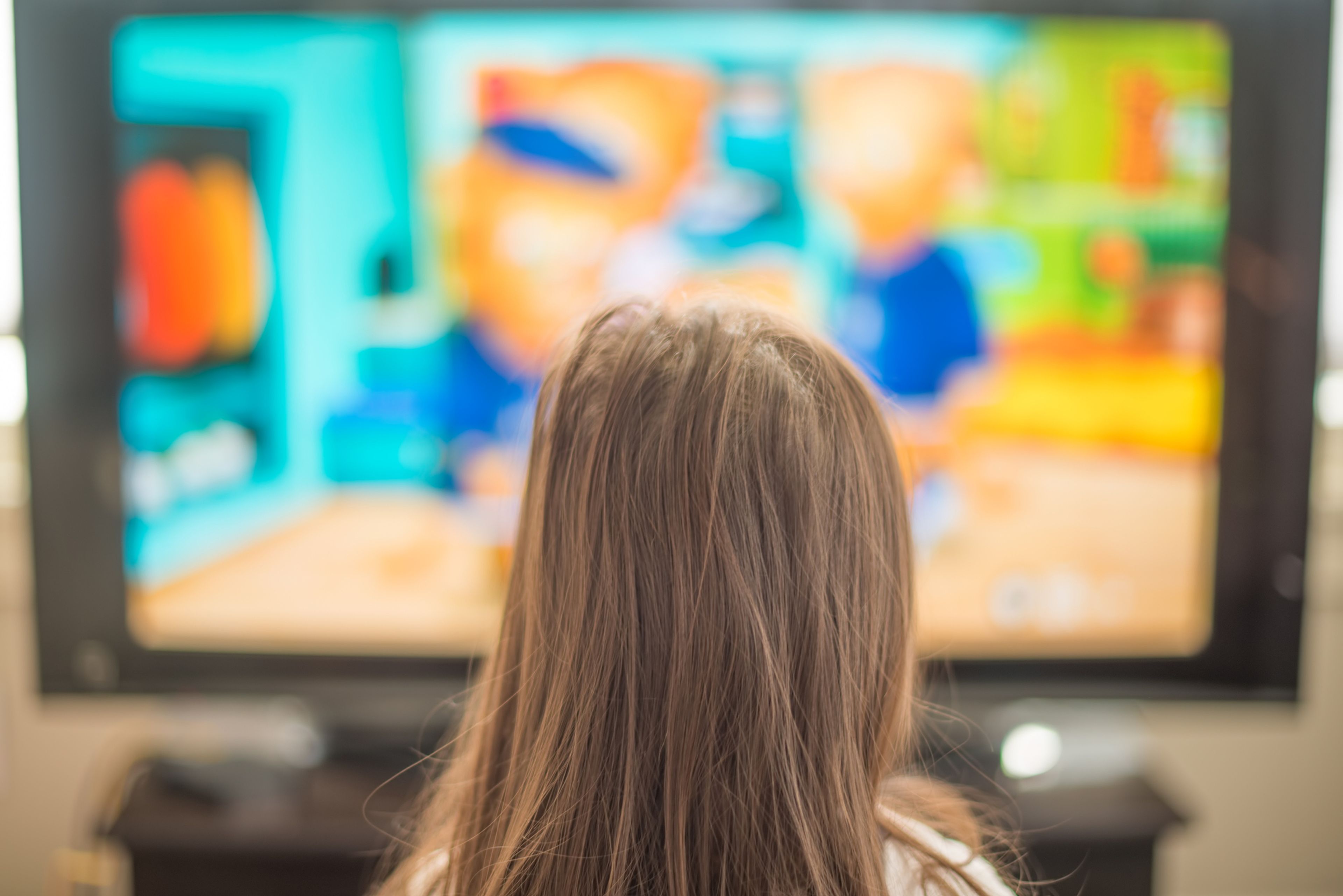 Una niña frente a una pantalla de televisión