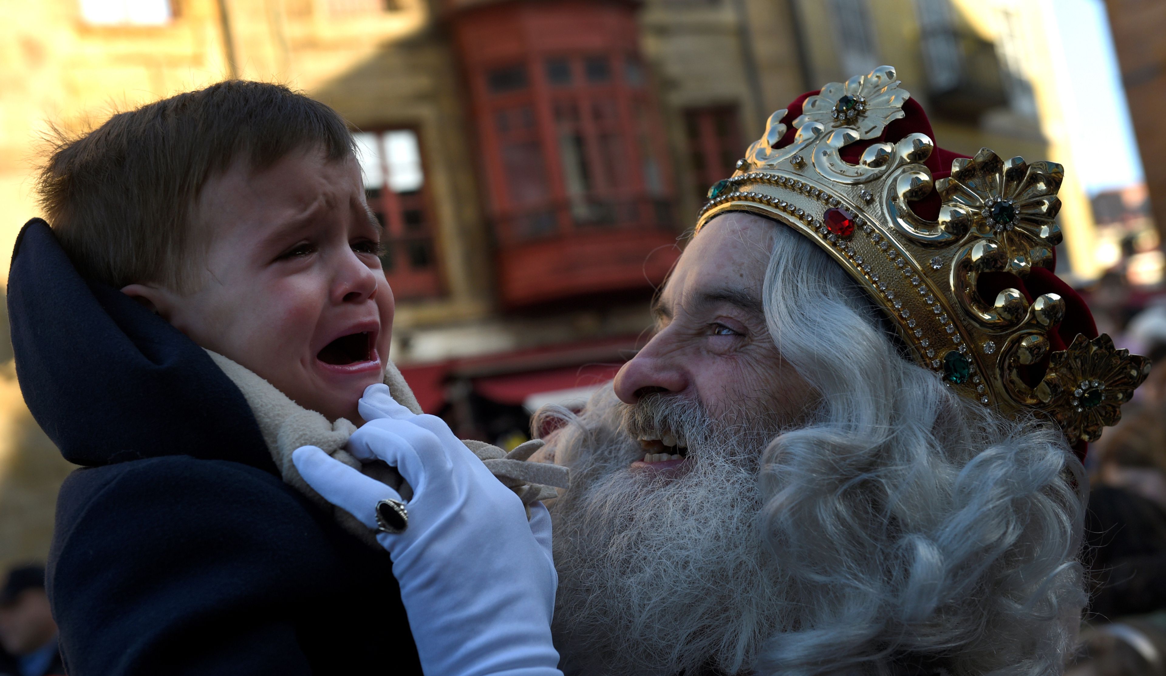 Un niño llora en brazos de un rey mago durante la cabalgata navideña de Gijón