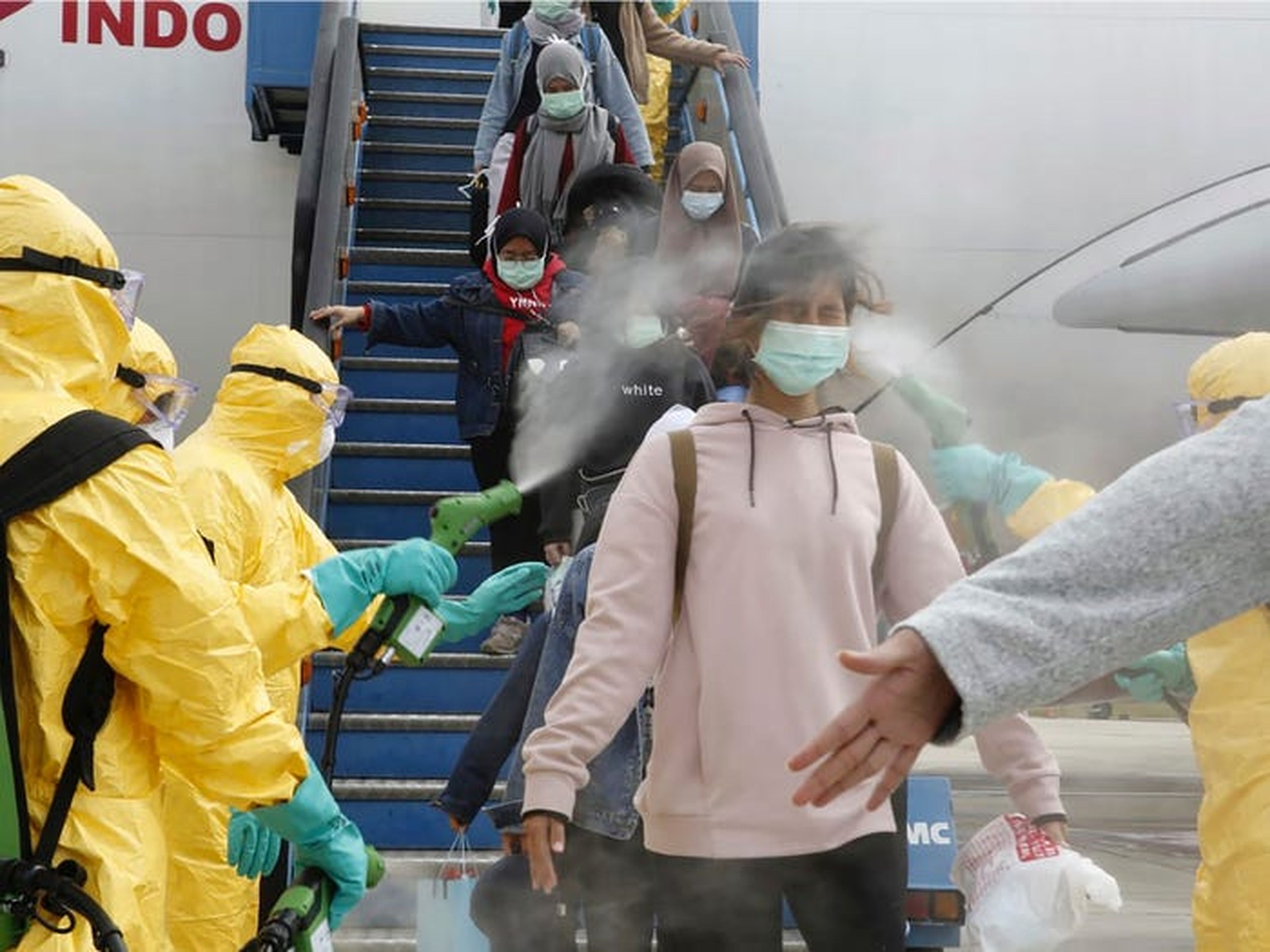 Los pasajeros indonesios que llegan de Wuhan son rociados con desinfectante en el aeropuerto Hang Nadim de Batam, el 2 de febrero.