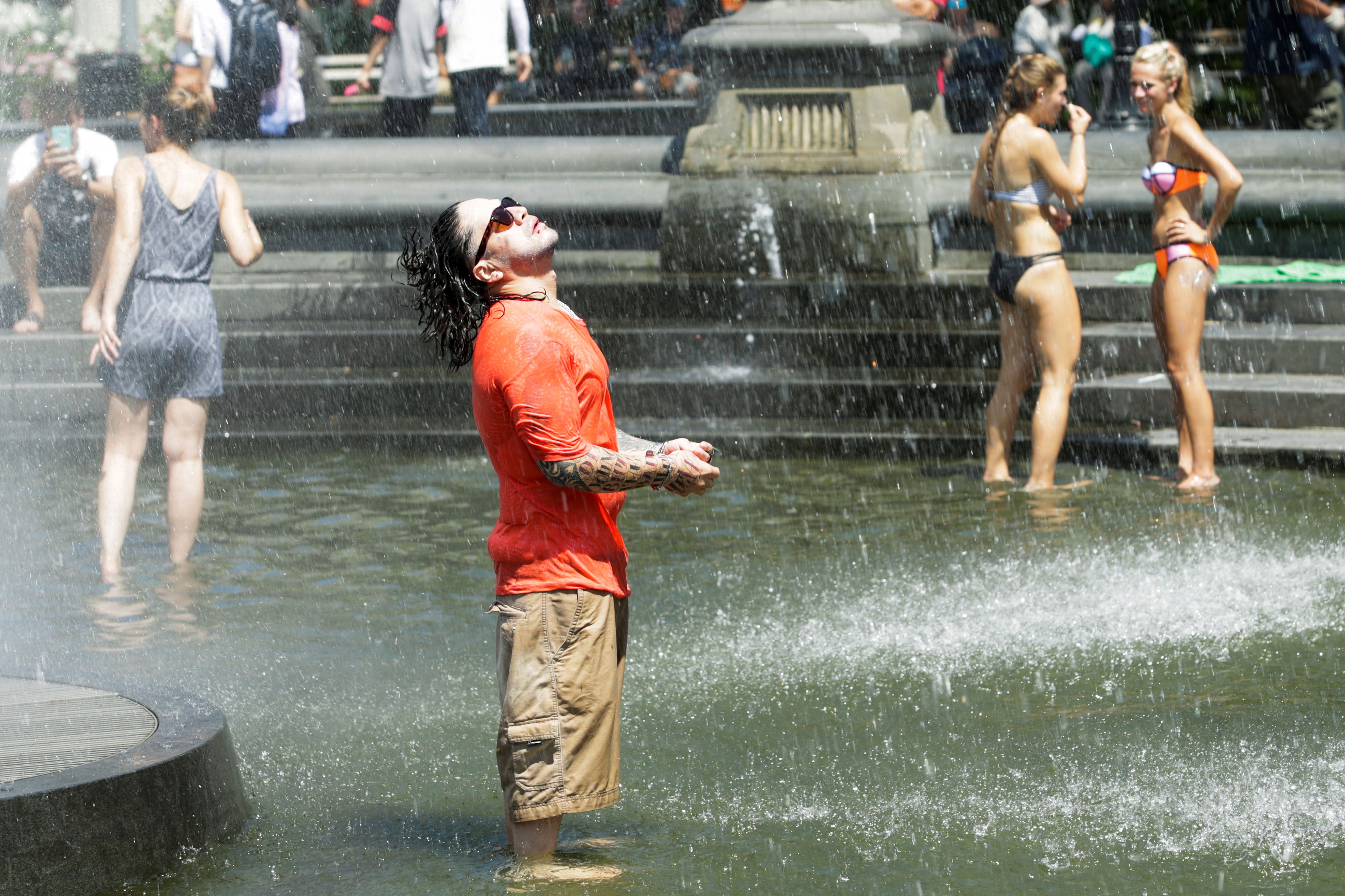 Personas bañándose en una fuente durante una ola de calor en Madrid.