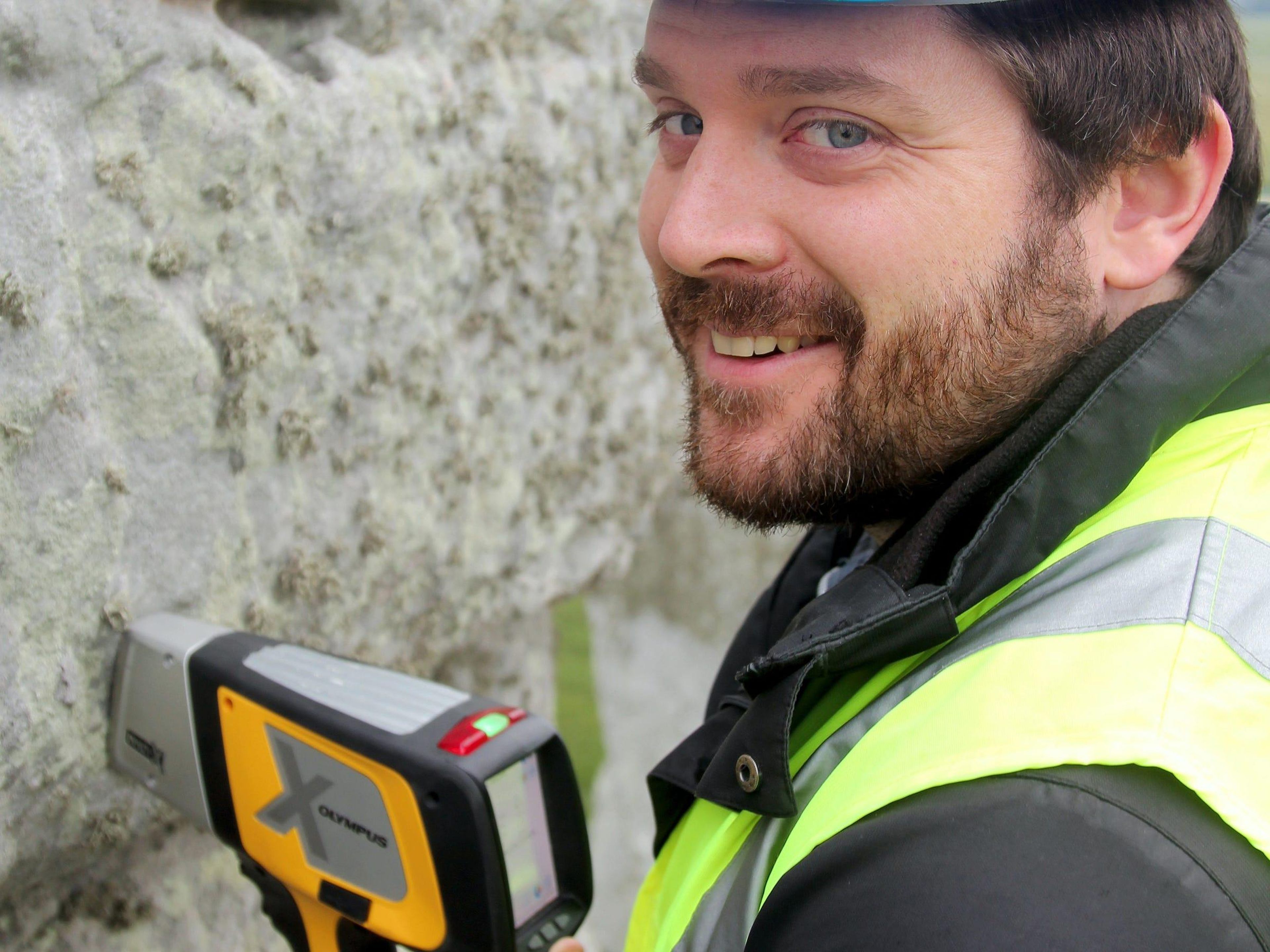 El investigador Jake Ciborowski analiza una piedra sarsen en Stonehenge utilizando un espectrómetro de fluorescencia de rayos X portátil.