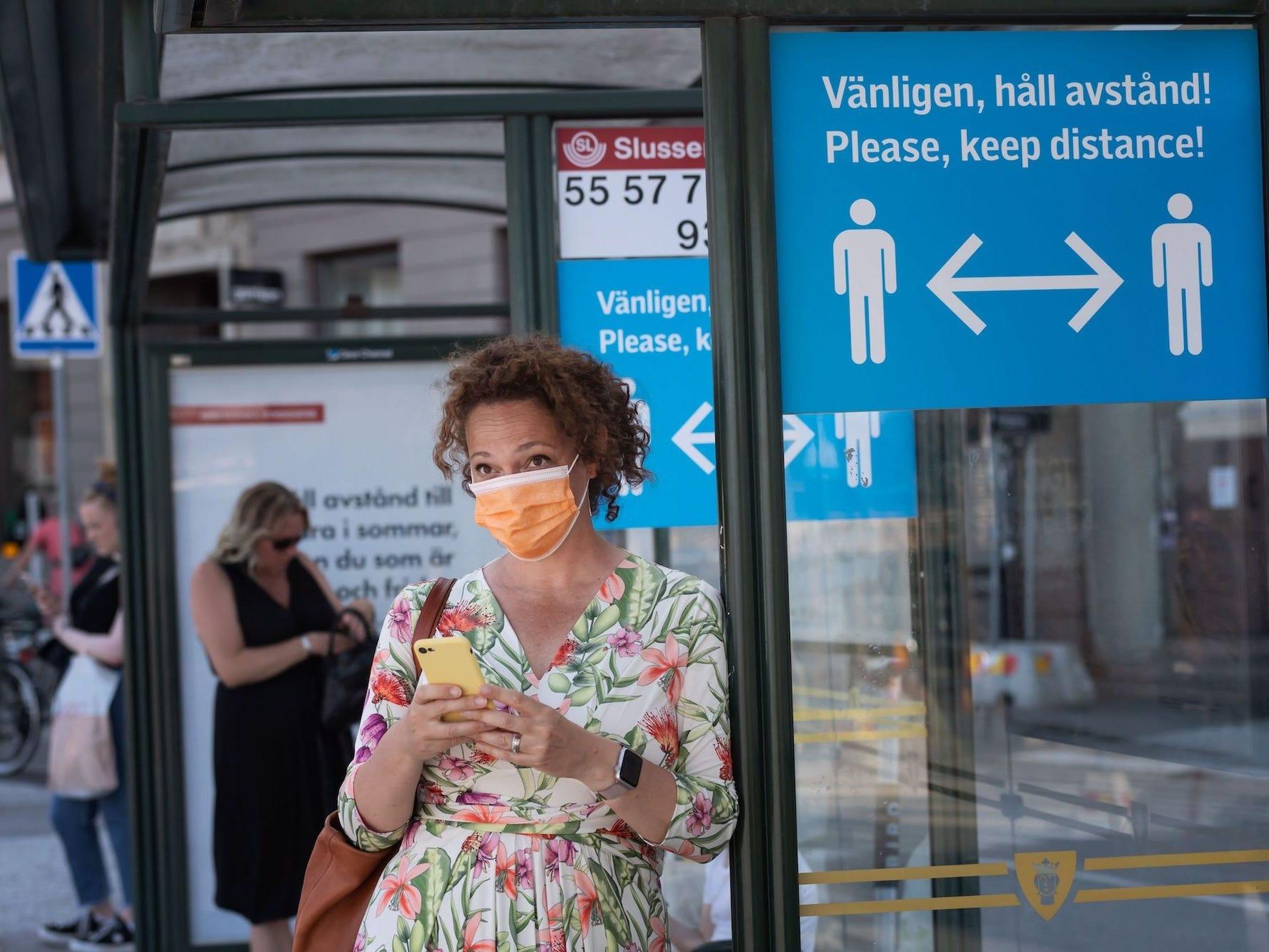 Una mujer lleva una mascarilla mientras espera en una parada de autobús el 26 de junio de 2020 en Estocolmo, Suecia.