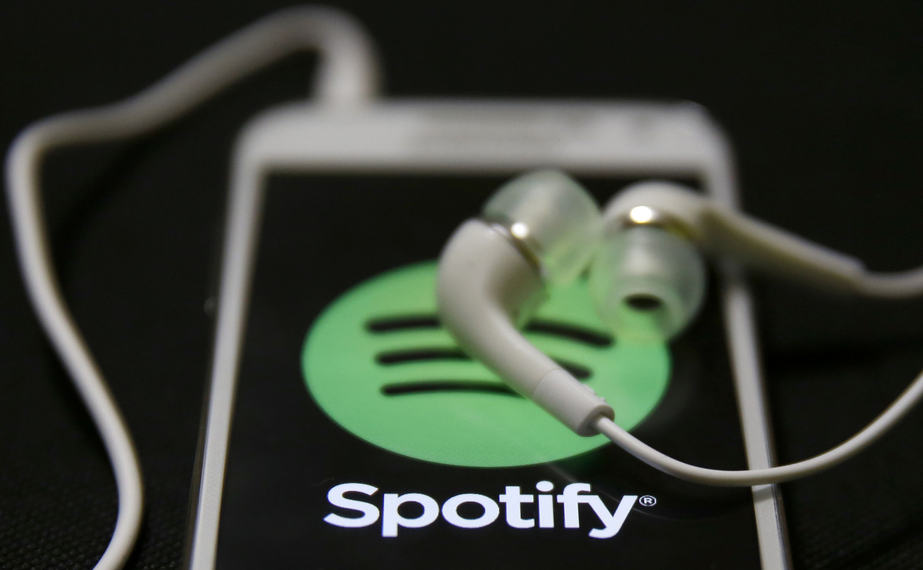 Unos auriculares sobre un móvil con el logo de Spotify