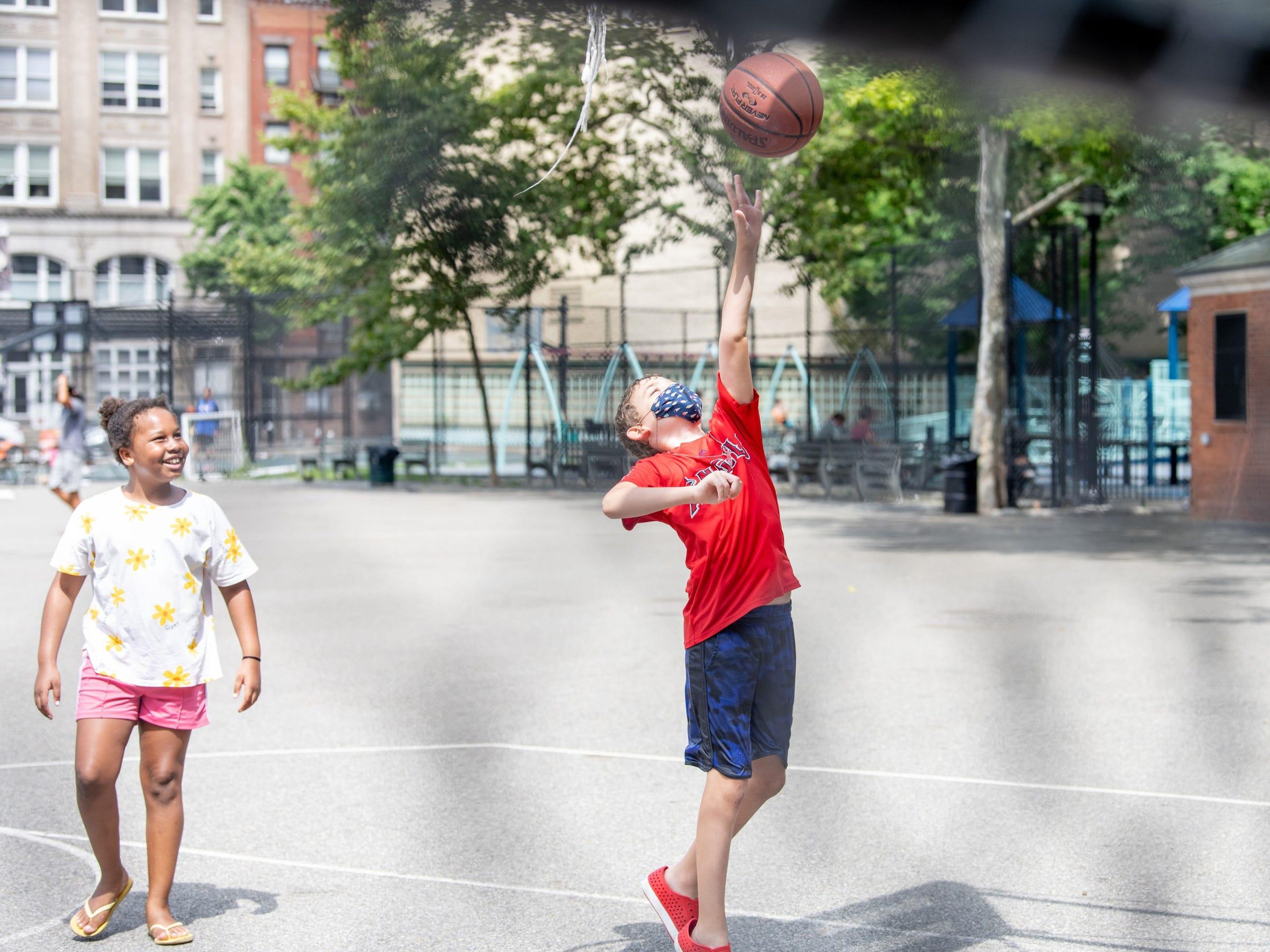 Two children play on a basketball court in New York City on July 30, 2020.