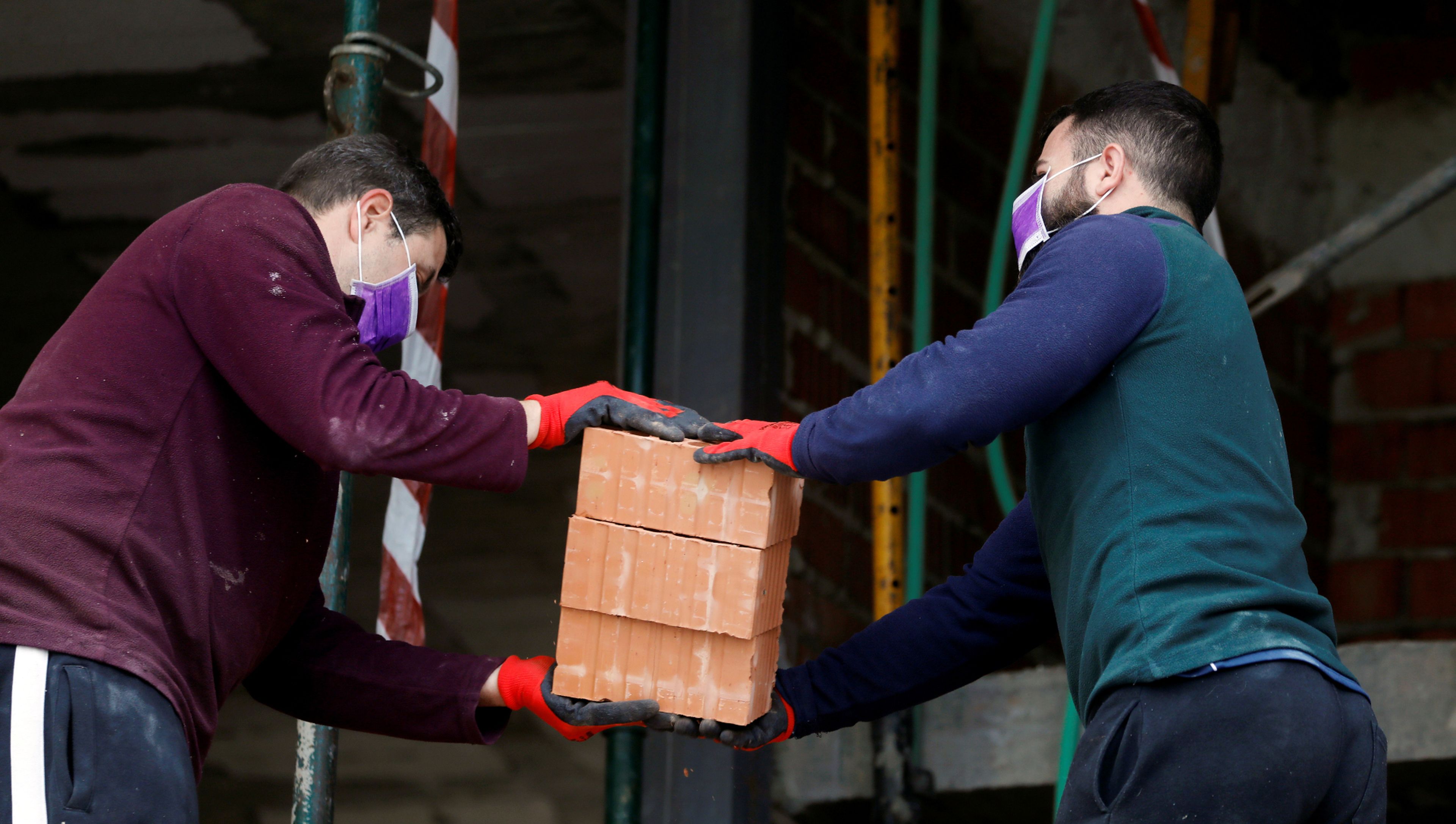 Dos obreros transportan ladrillos en la construcción de una vivienda en Ronda (Málaga)