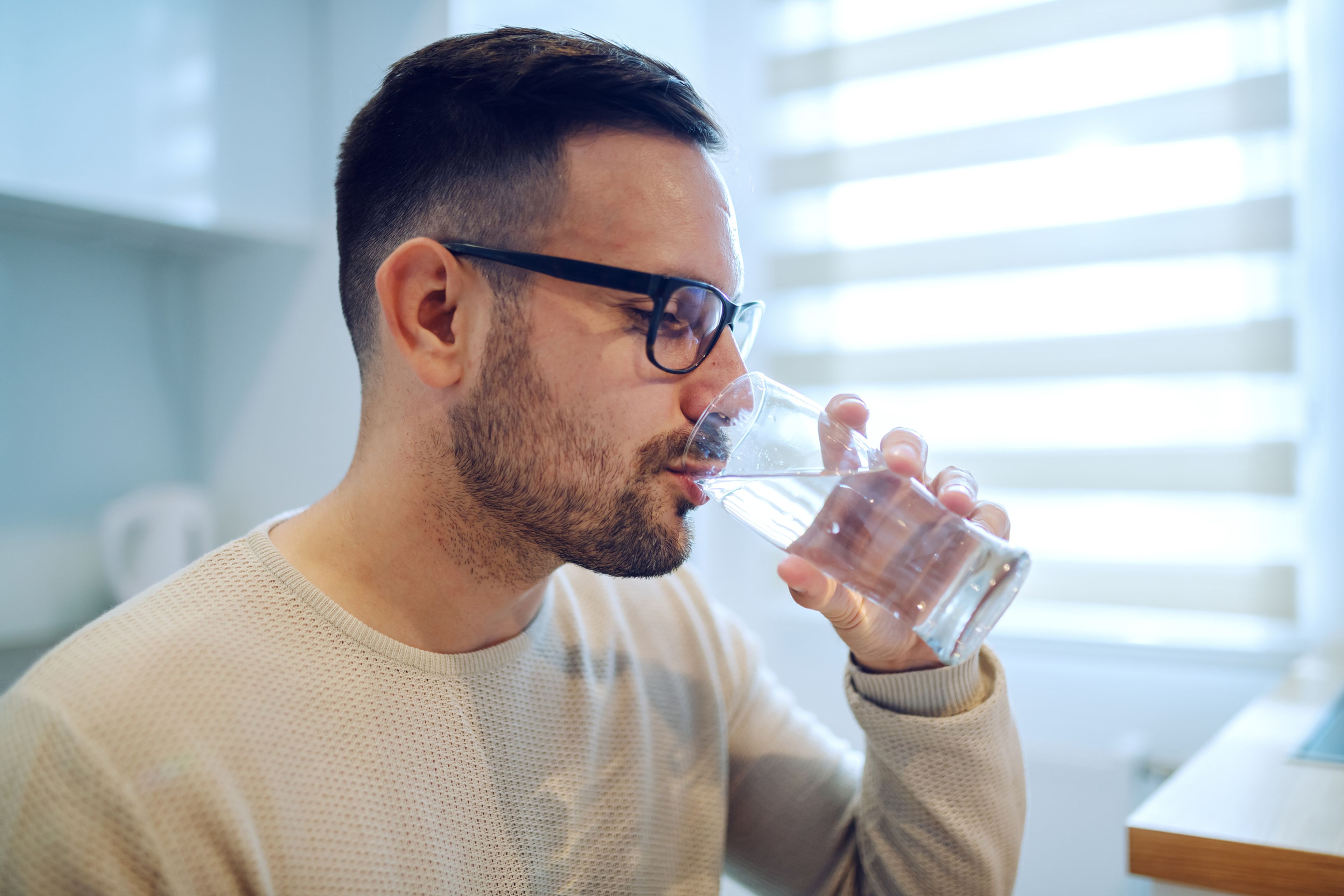 Hombre bebiendo agua en un vaso.