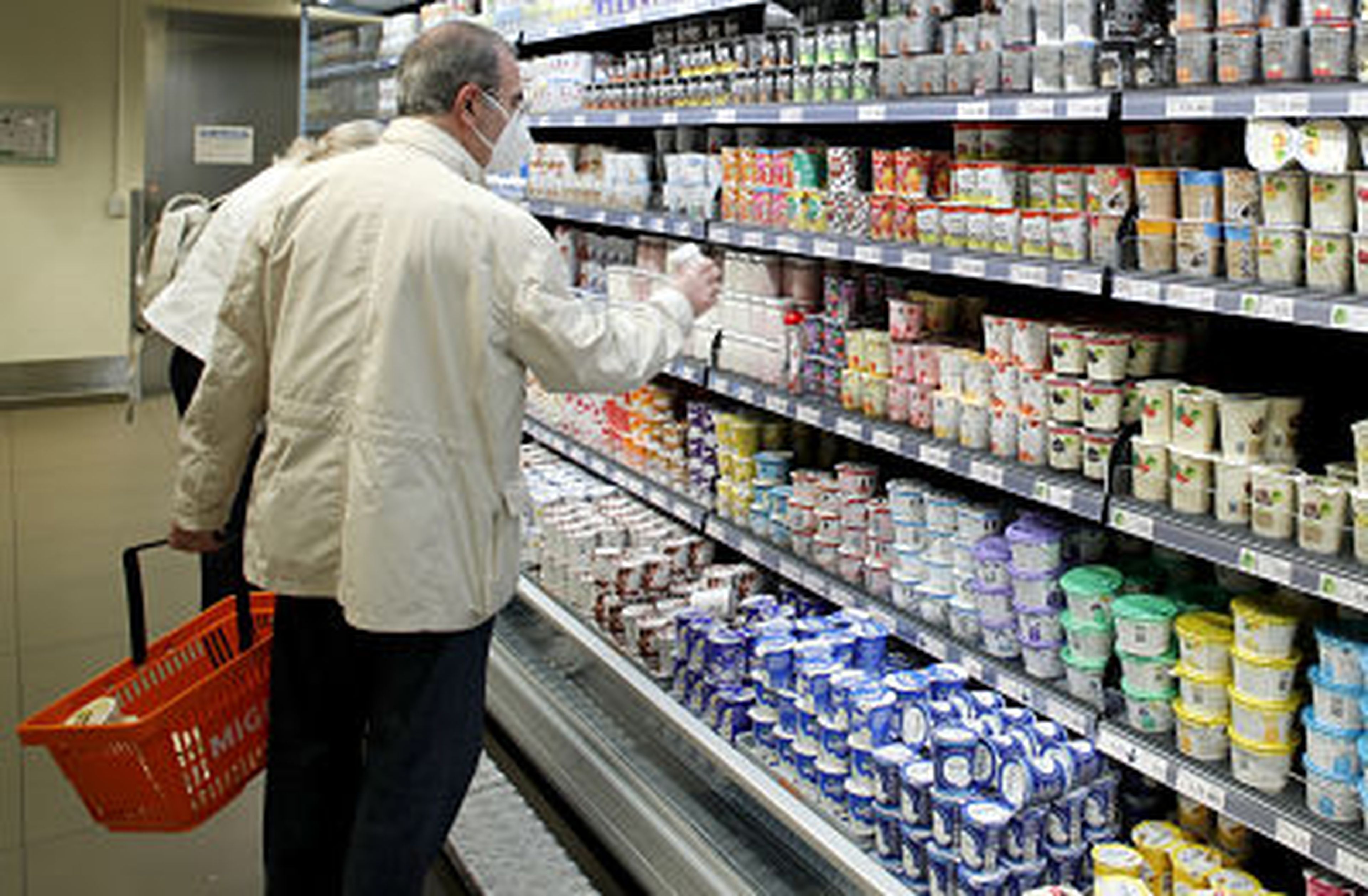 Un hombre cogiendo algo de la estantería de un supermercado