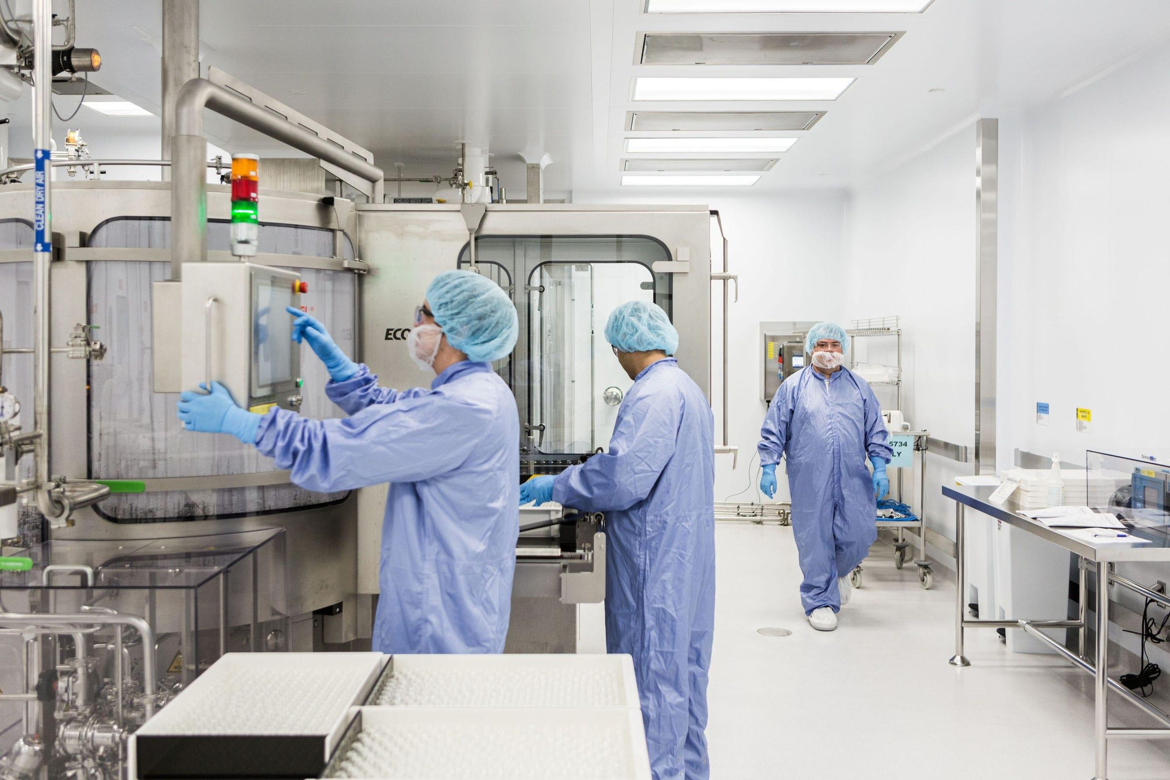 Los técnicos de laboratorio operan una máquina para lavar los frascos vacíos de remdesivir en una instalación de Gilead Sciences en La Verne