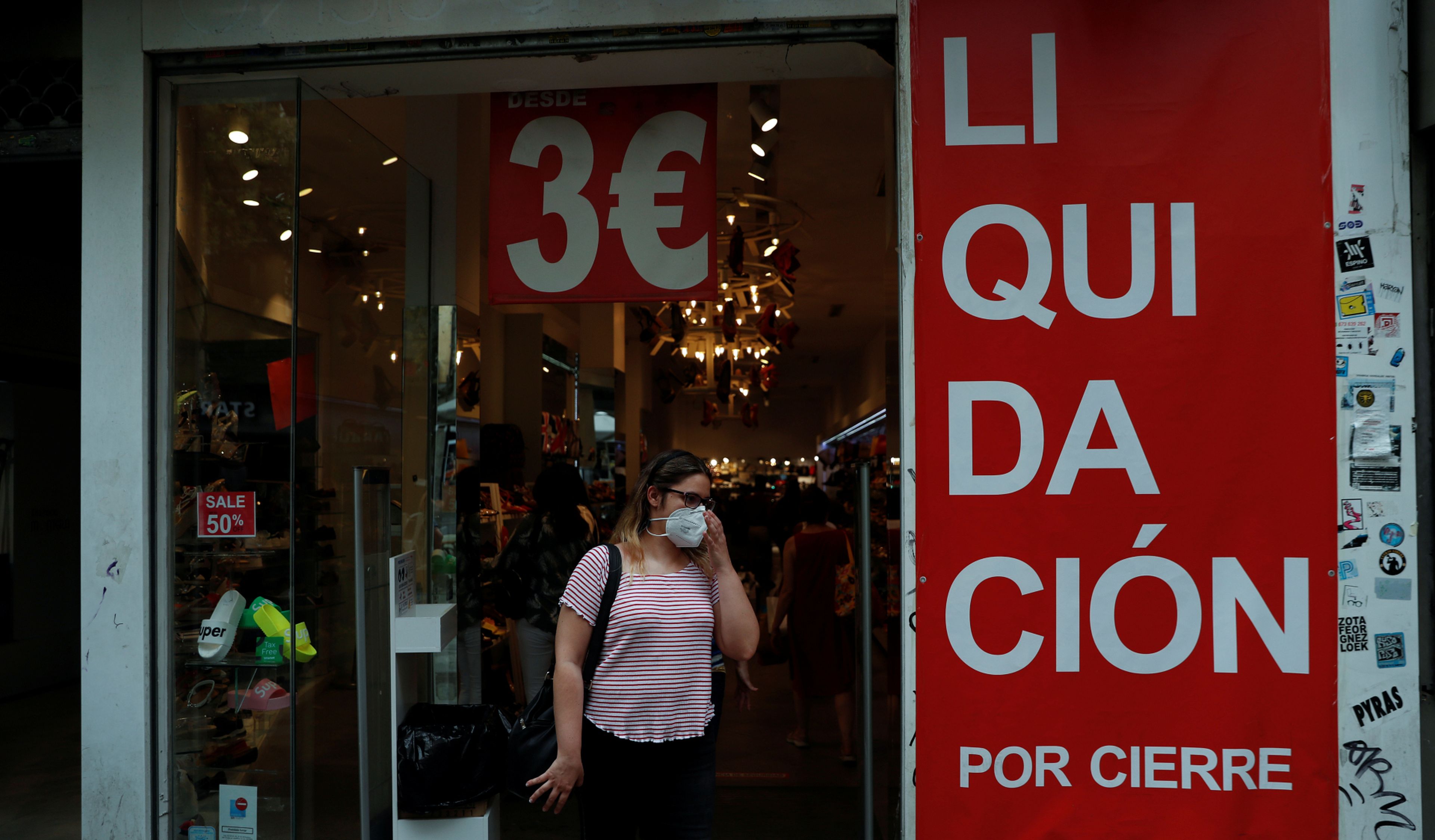 Una mujer se ajusta su mascarilla a la salida de una tienda en liquidación por cierre en Madrid
